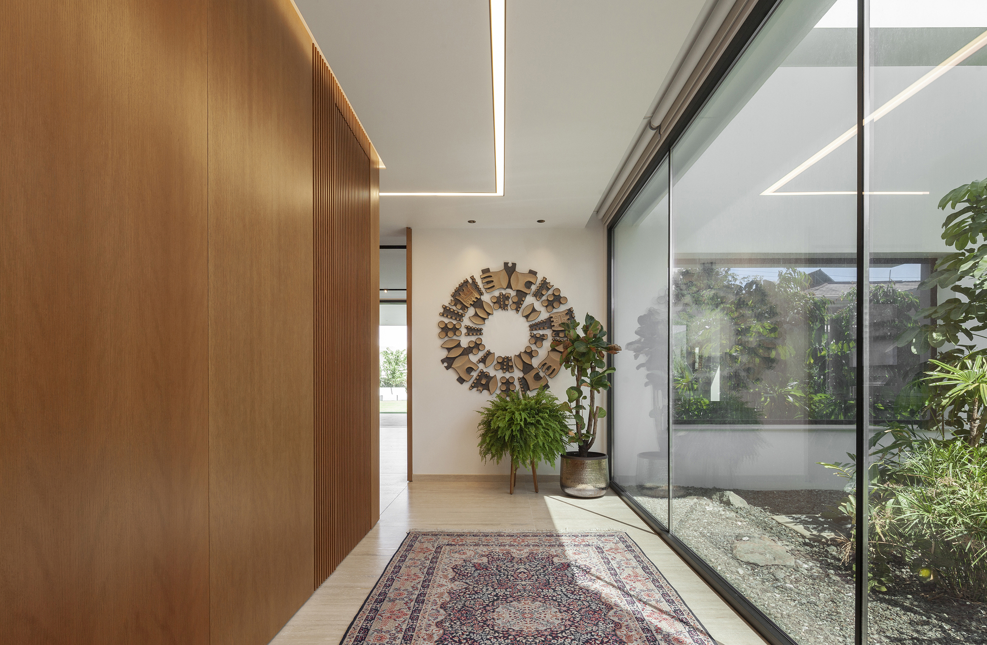 Entry hall with timber wall paneling and glass wall overlooking internal planted courtyard
