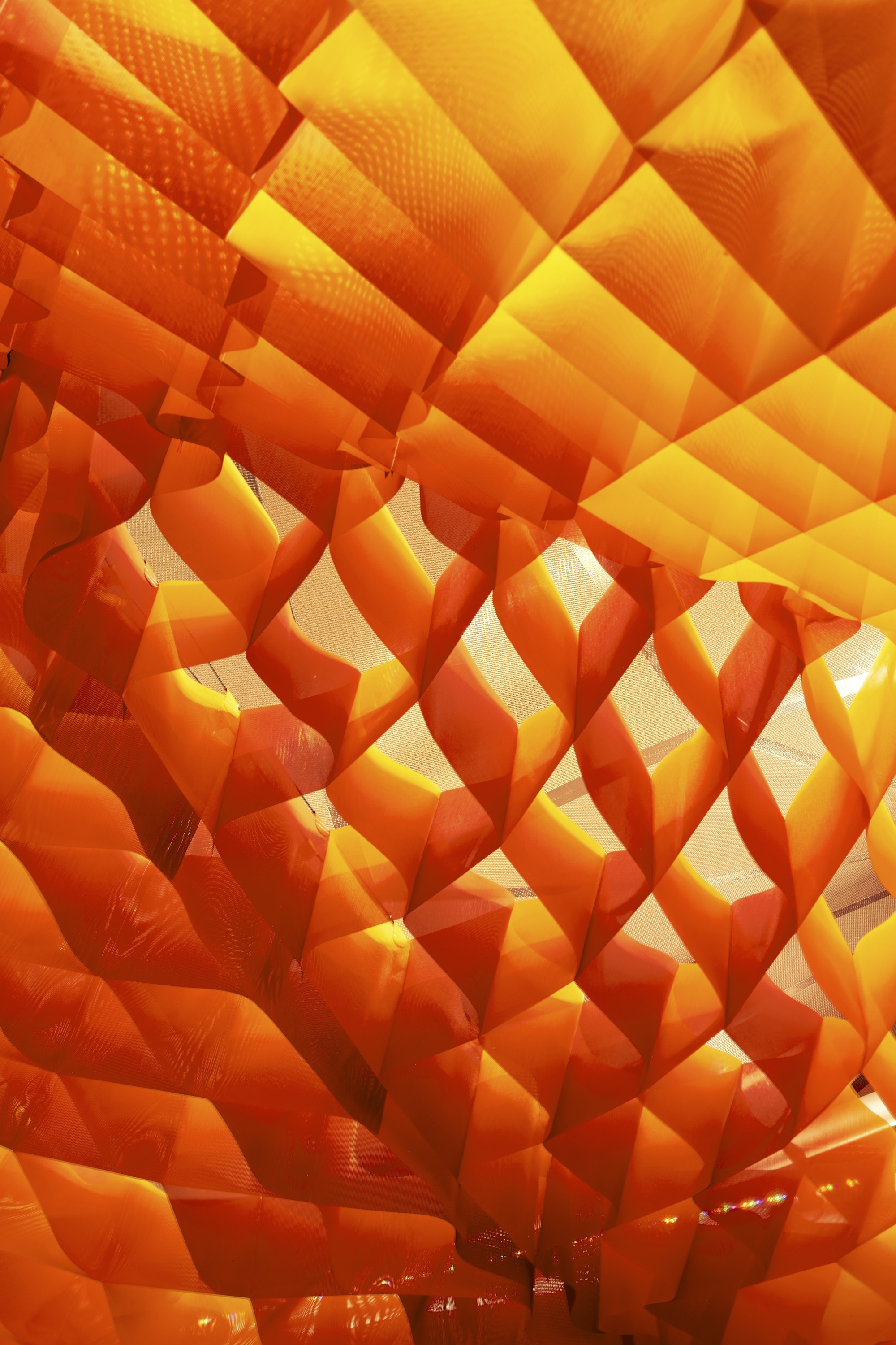 Close-up of the layered orange fabric panels with perforations creating a gradated diamond pattern