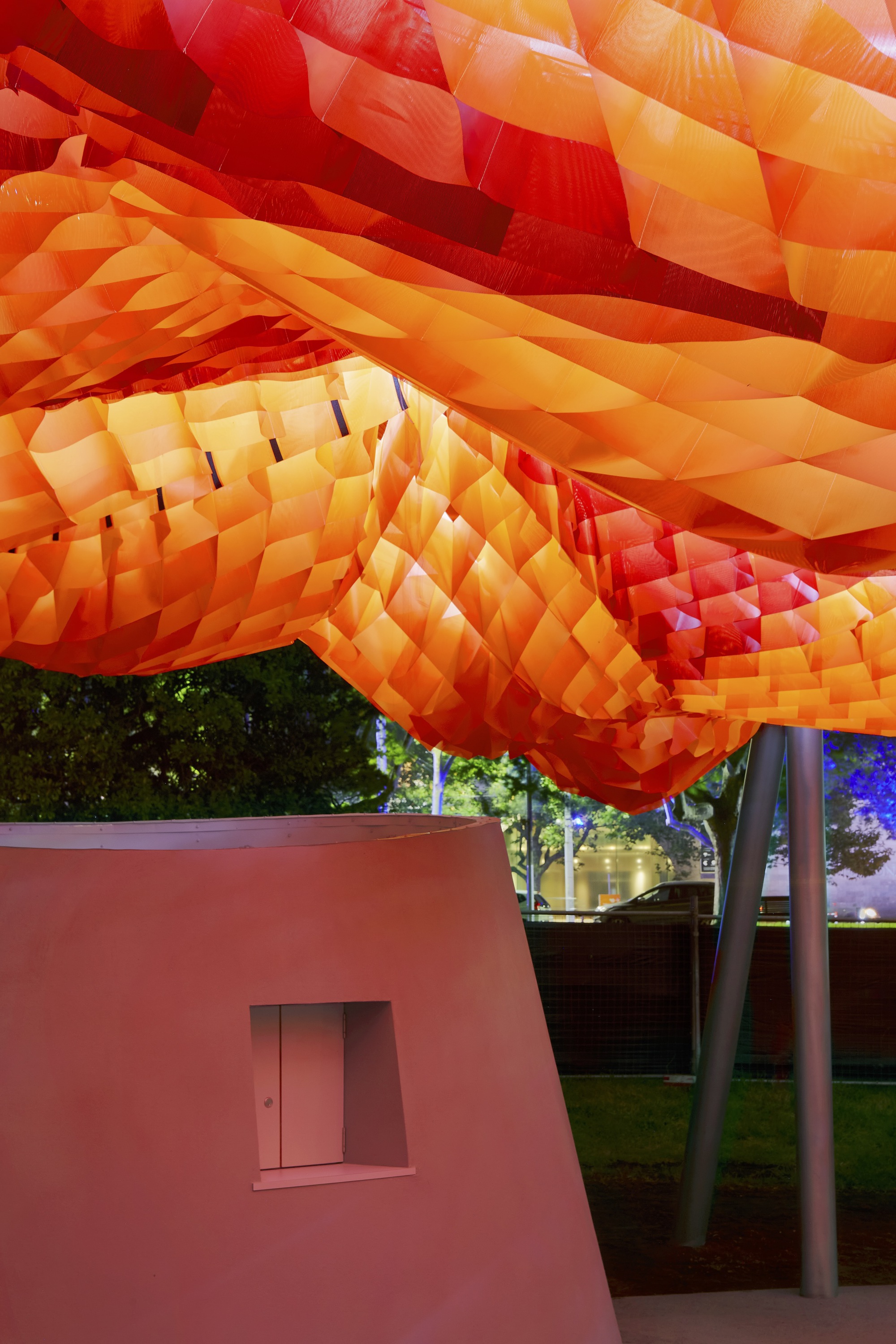 Close-up of the orange and red fabric waffle canopy suspended above a pink pavilion volume