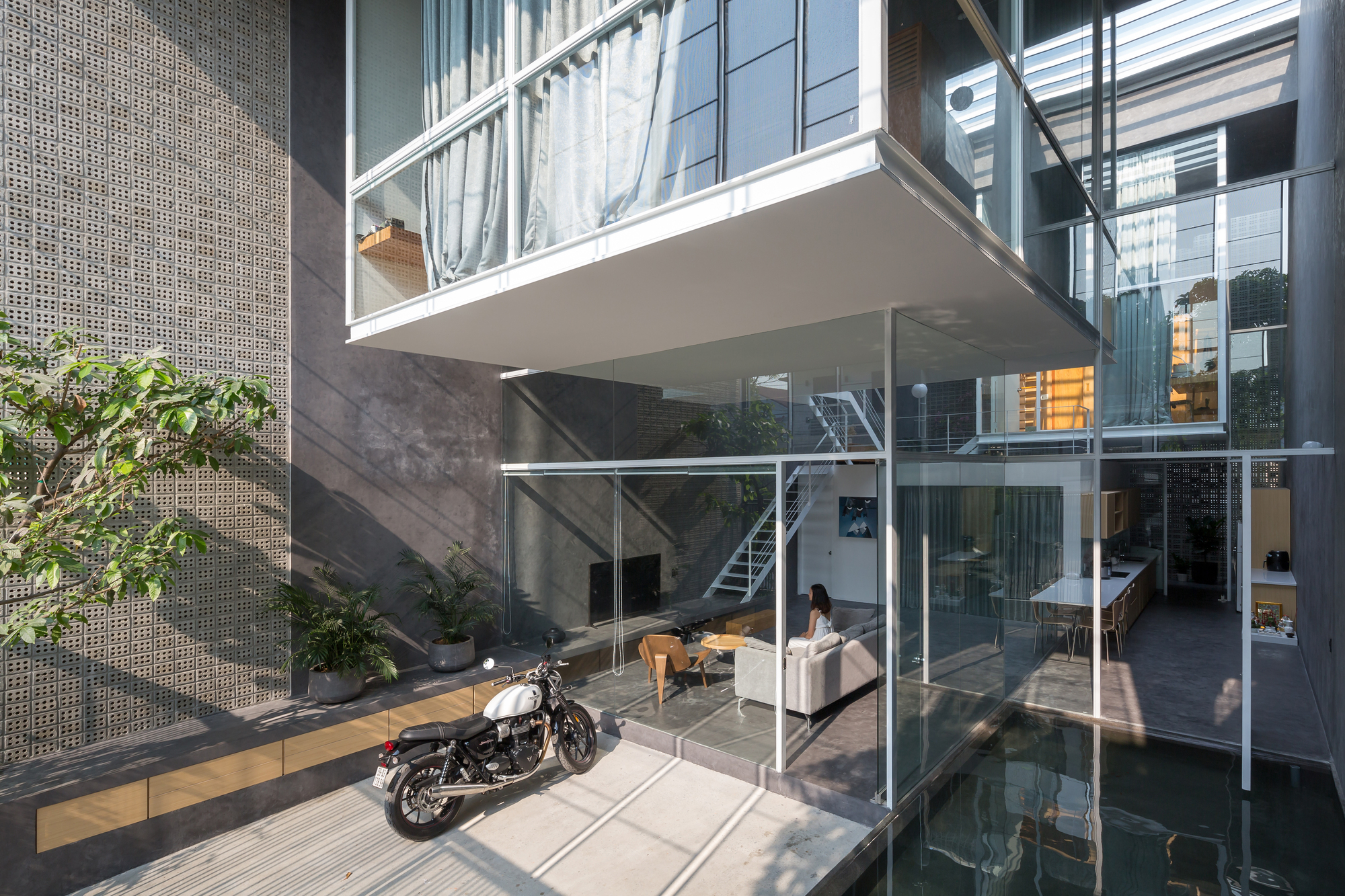 Triple-height interior courtyard with motorcycle parked on the concrete ground floor beneath stacked balconies
