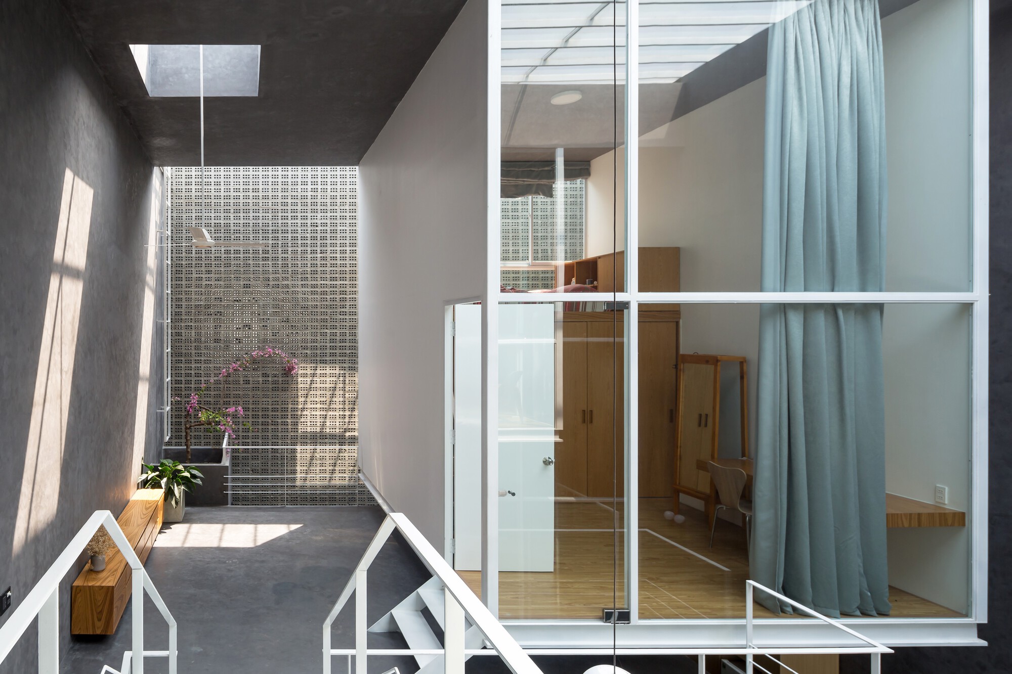 Interior balcony overlooking perforated metal screen wall with skylight above casting morning shadows