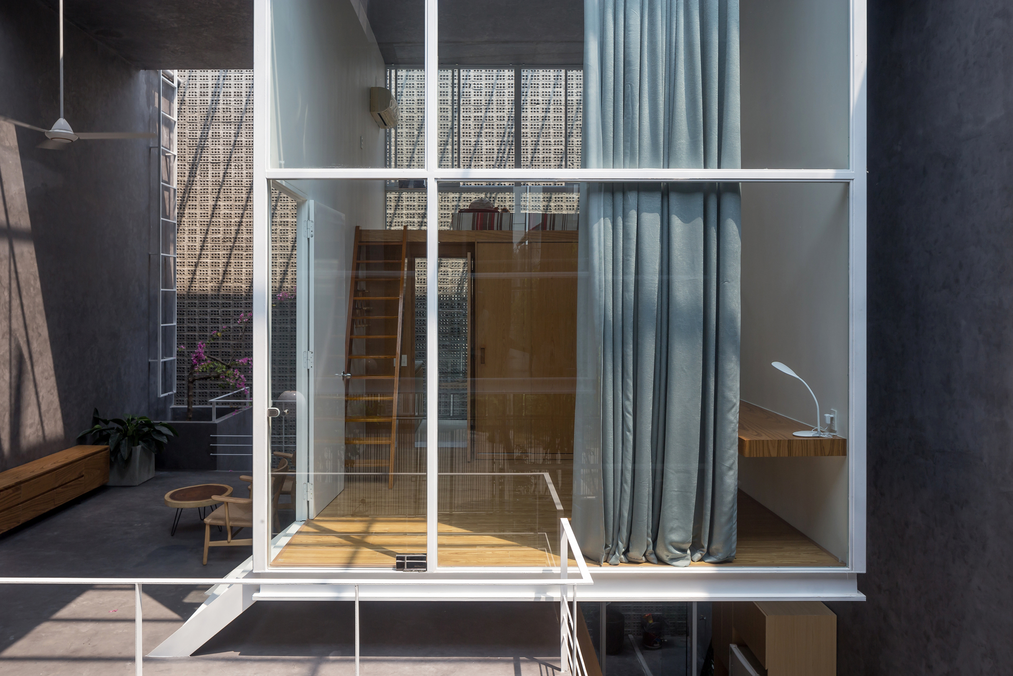 Glass-walled bedroom module with timber flooring suspended above the lower courtyard level
