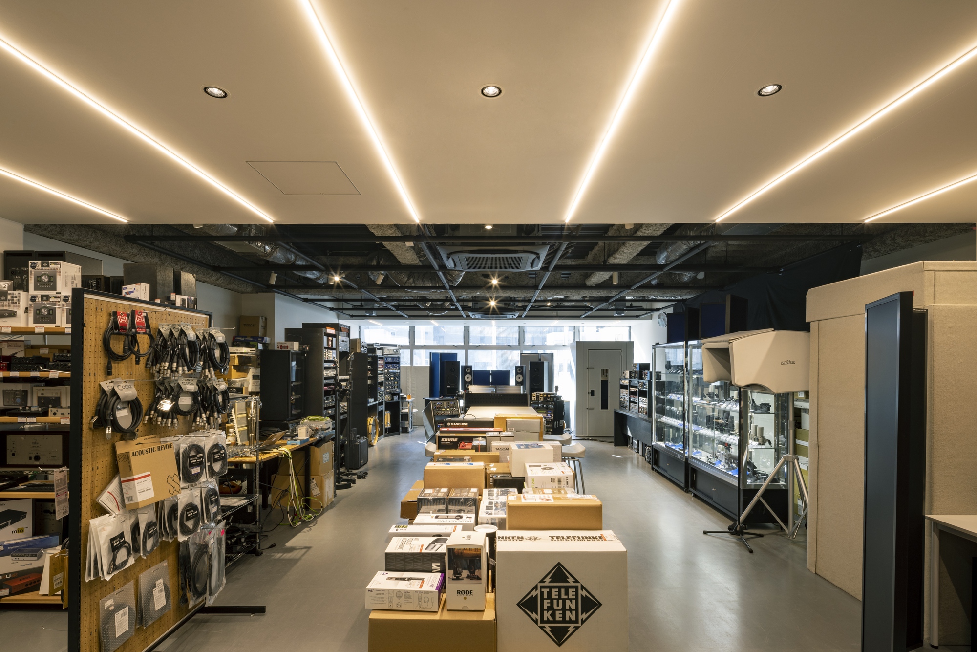 Retail interior with linear LED ceiling coves above exposed black ductwork and merchandise displays