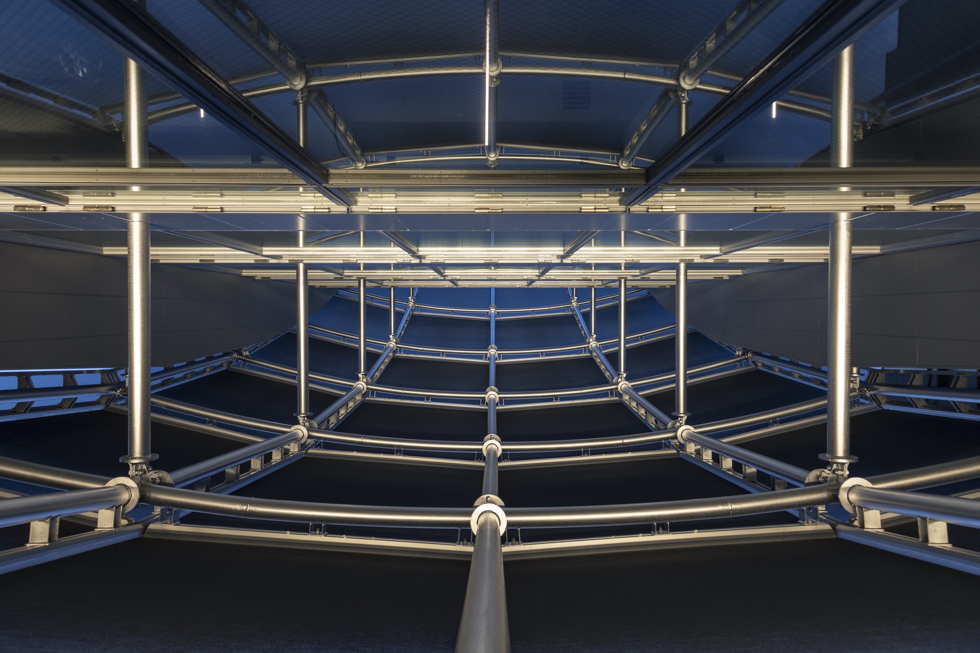 Upward view of circular steel structural rings with LED strips at dusk