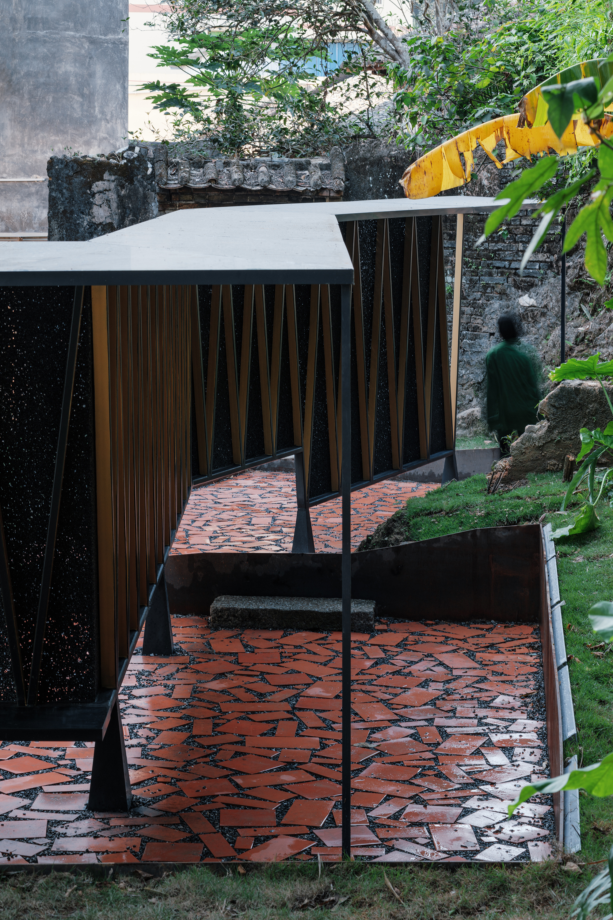 Pavilion interior with timber slat walls and white roof canopy seen from red terracotta paved terrace