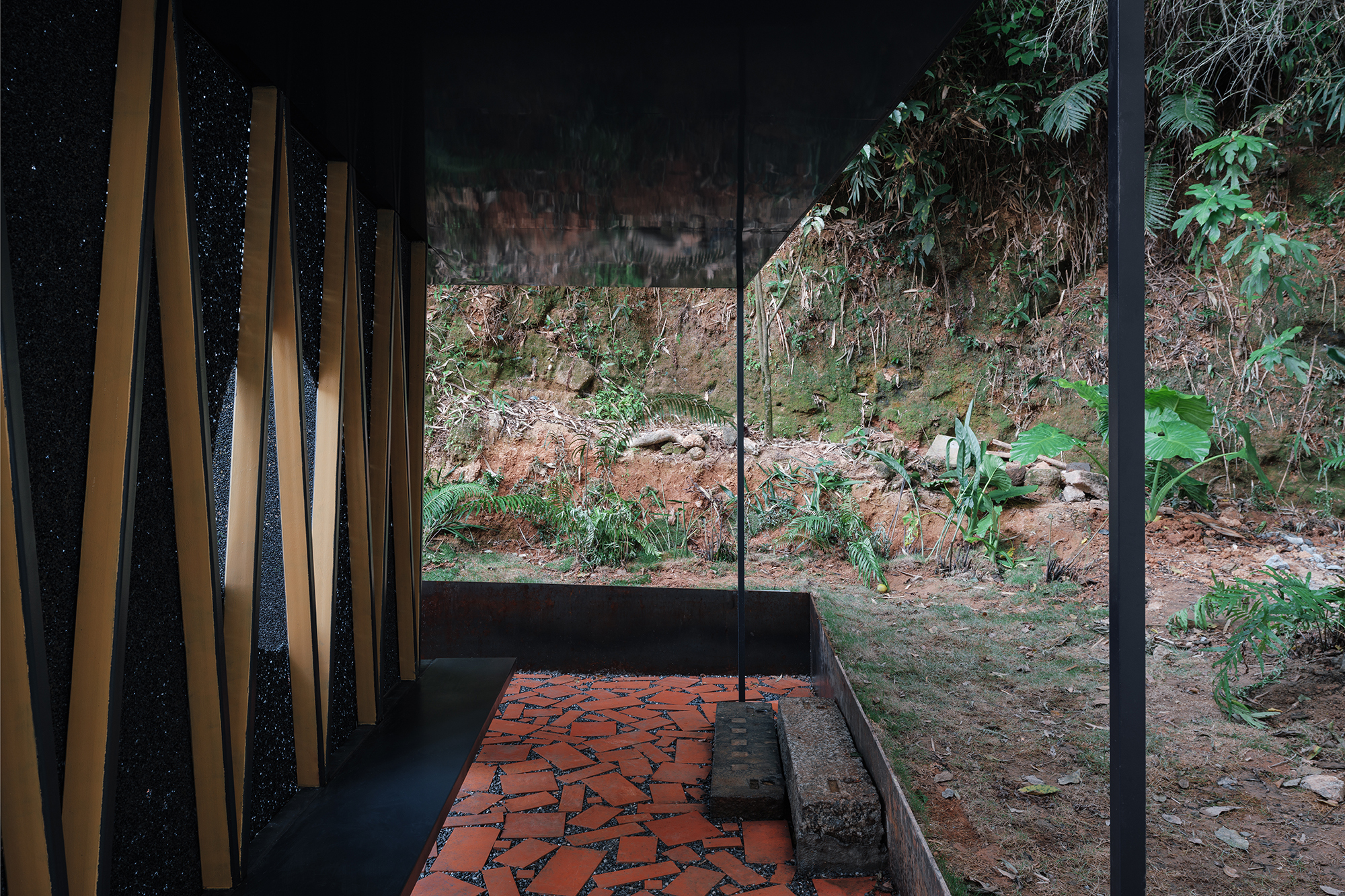 Interior view through timber slat screen toward hillside with vegetation and fallen leaves