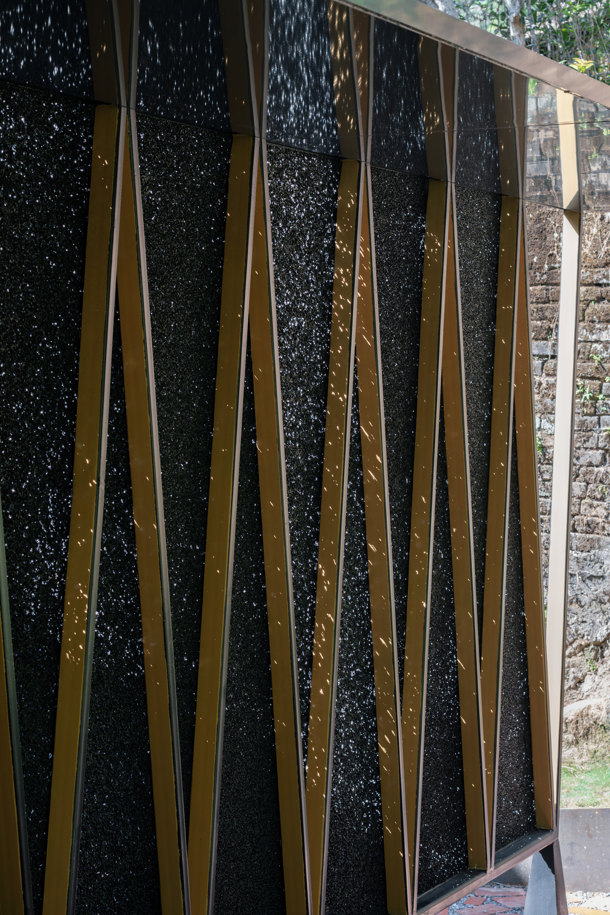 Close-up of the textured black panel system held by crossed bronze metal straps with visible rivets