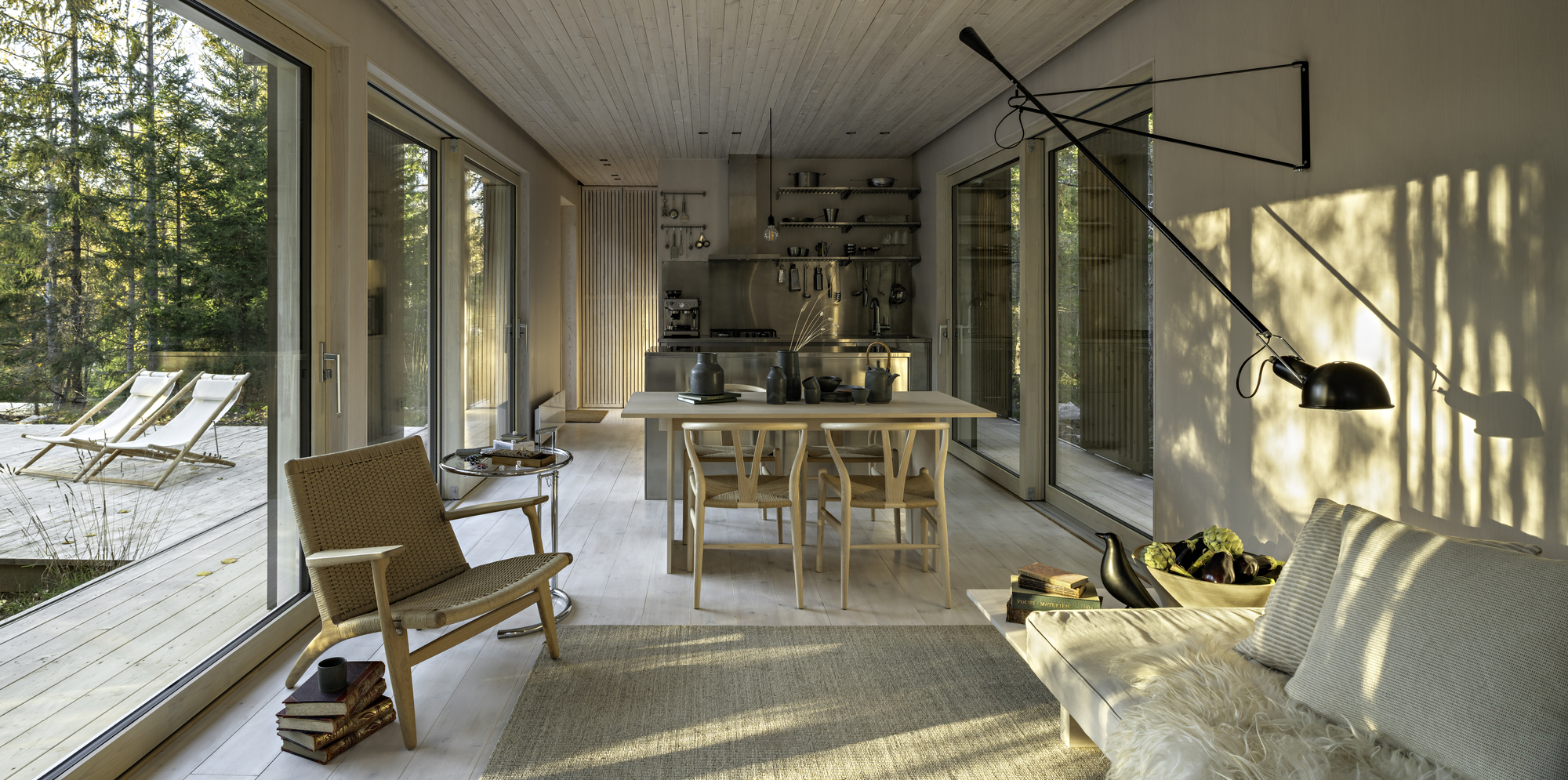 Open living and dining area with floor-to-ceiling glass and dappled afternoon light