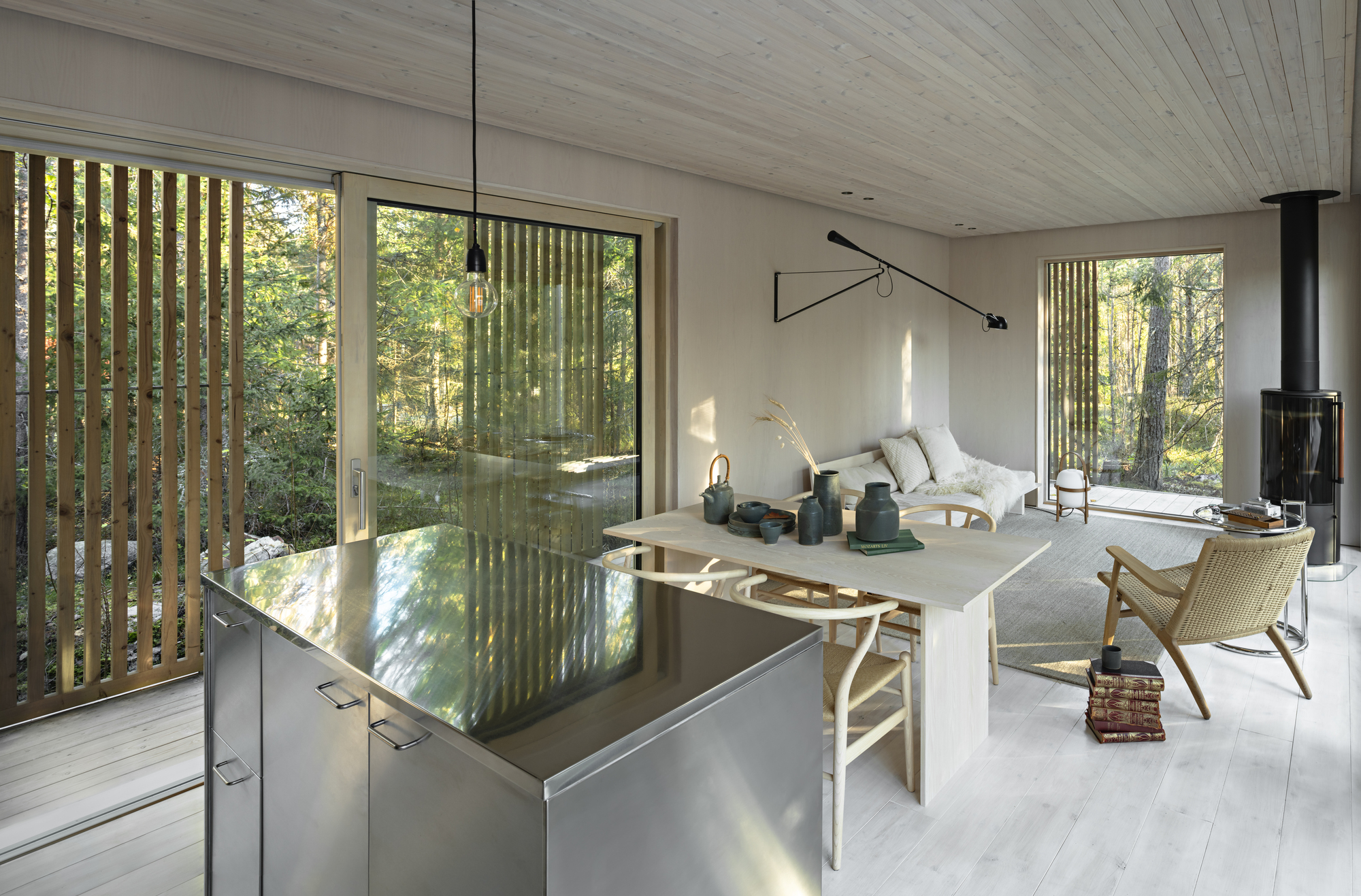 Open living space with stainless steel kitchen island and vertical timber screens filtering daylight