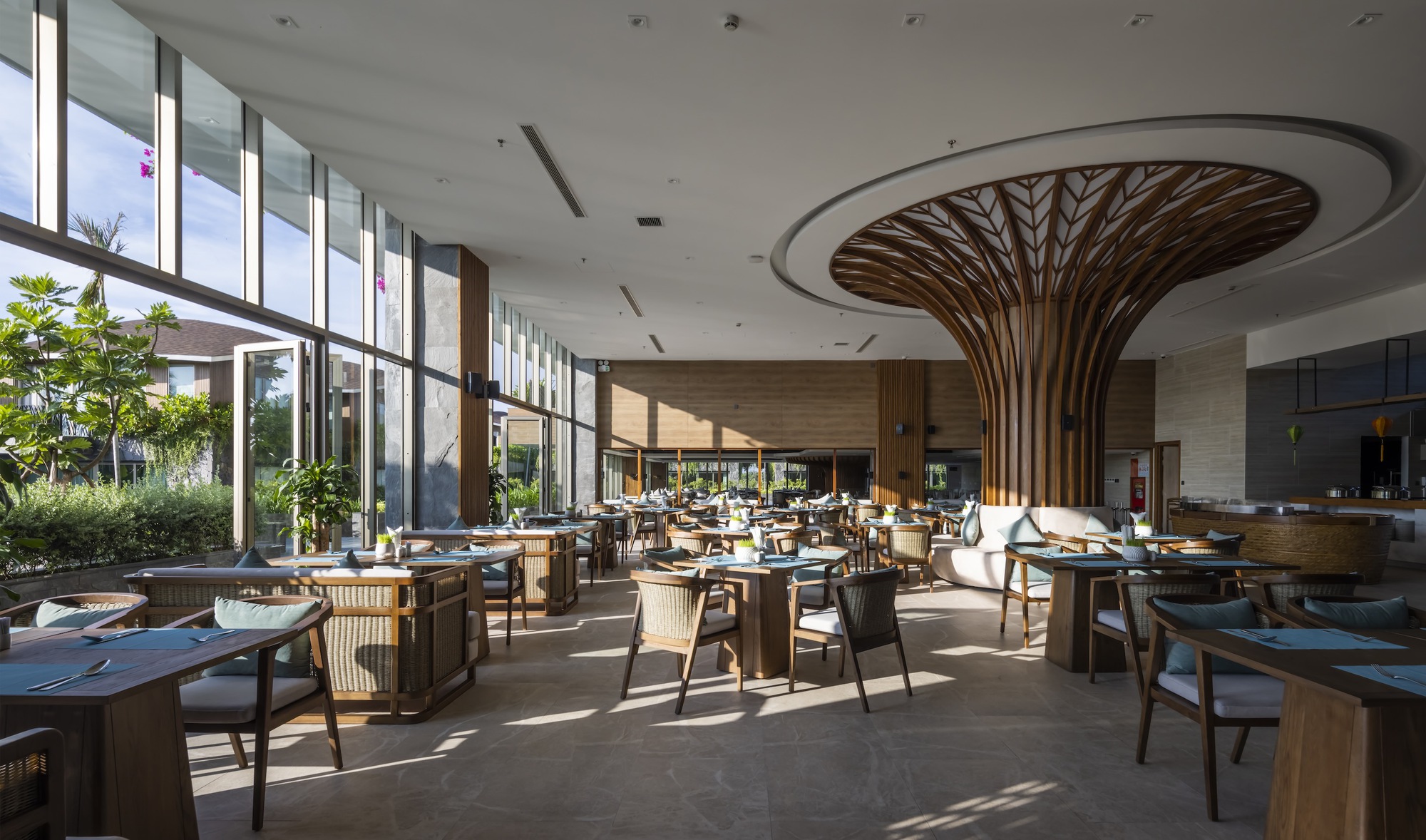 Dining area with a branching timber column supporting a circular ceiling recess under skylights