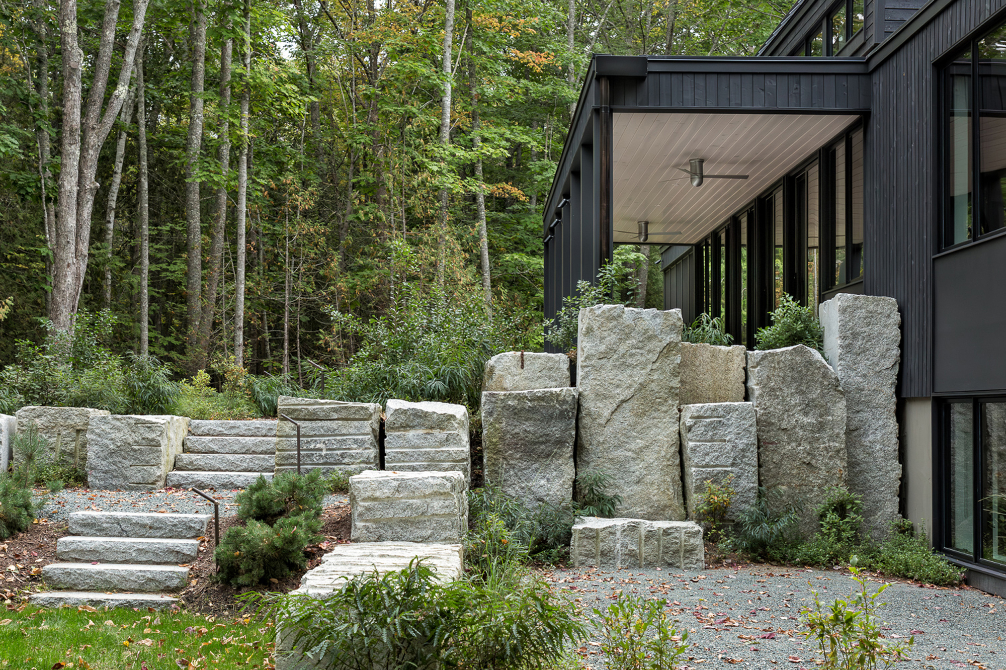 Stacked granite blocks forming a retaining wall with integrated stairs leading to the covered entry porch