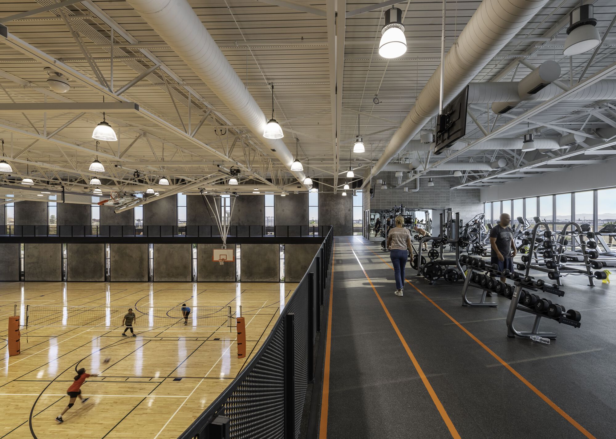 Basketball court alongside fitness area with exposed ductwork and wood slat ceiling