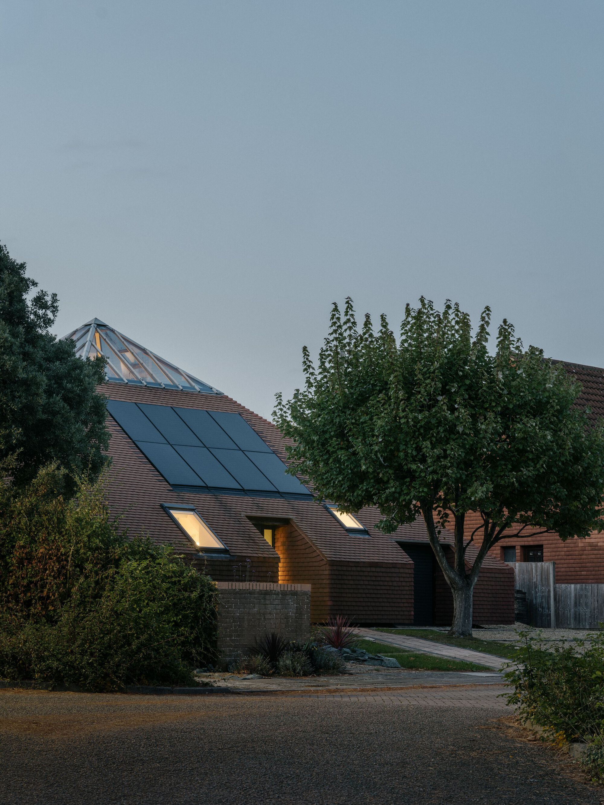 Street view of the tiled roof with integrated solar panels and skylight at dusk