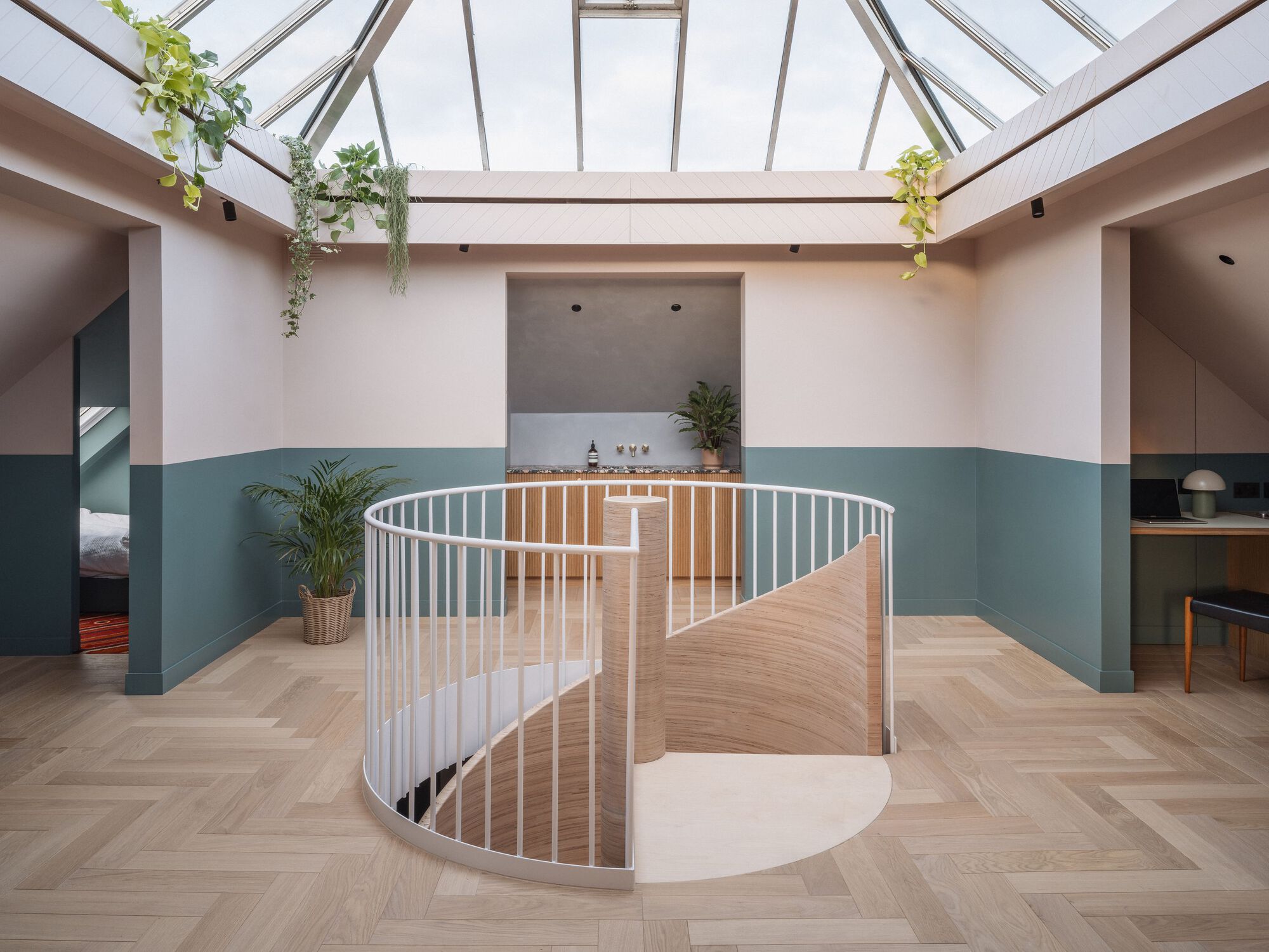 Upper level gallery with glazed skylight roof and curved stair opening with hanging plants