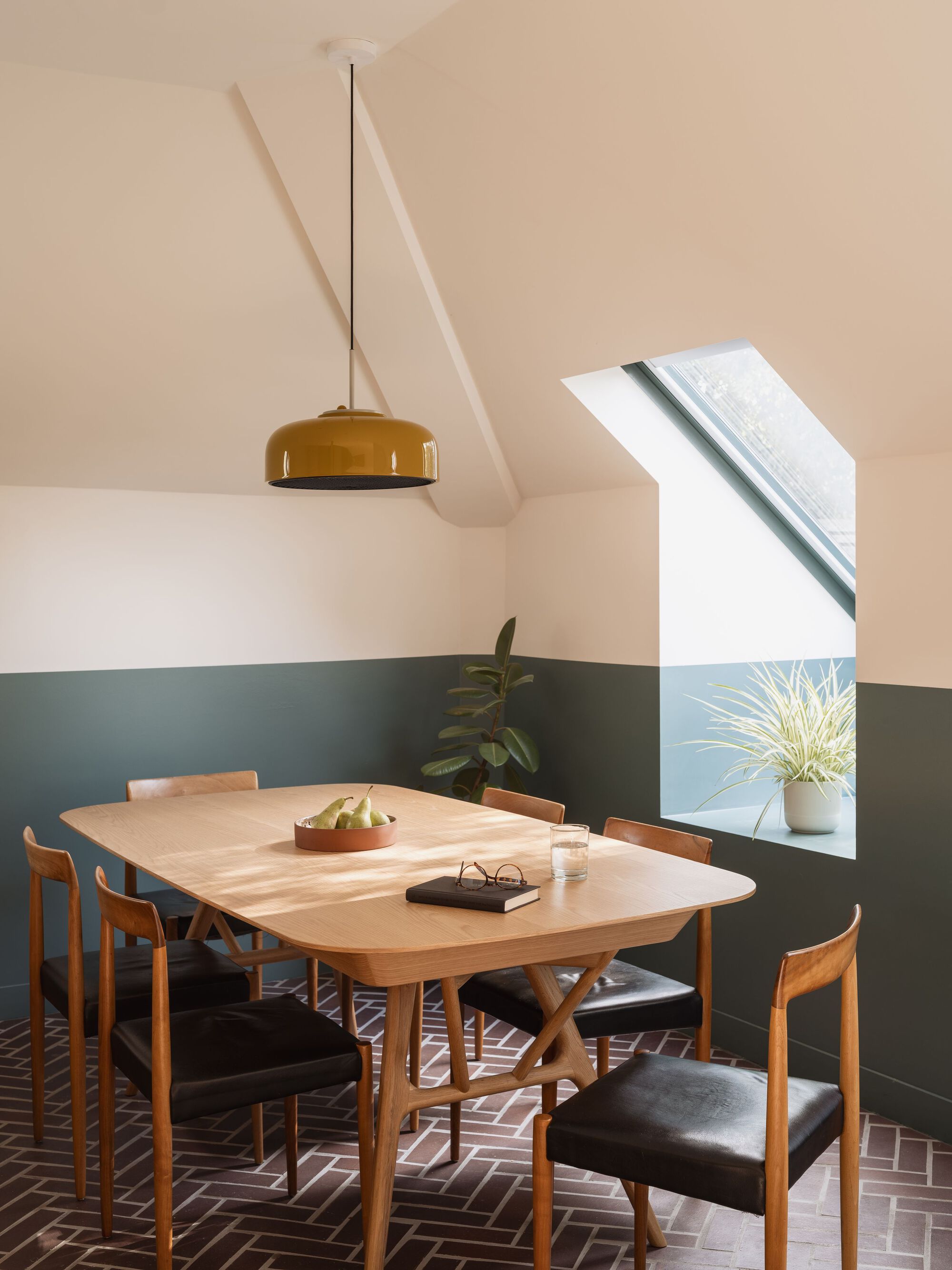 Dining room with brass pendant light and angled skylight illuminating the terrazzo tile floor