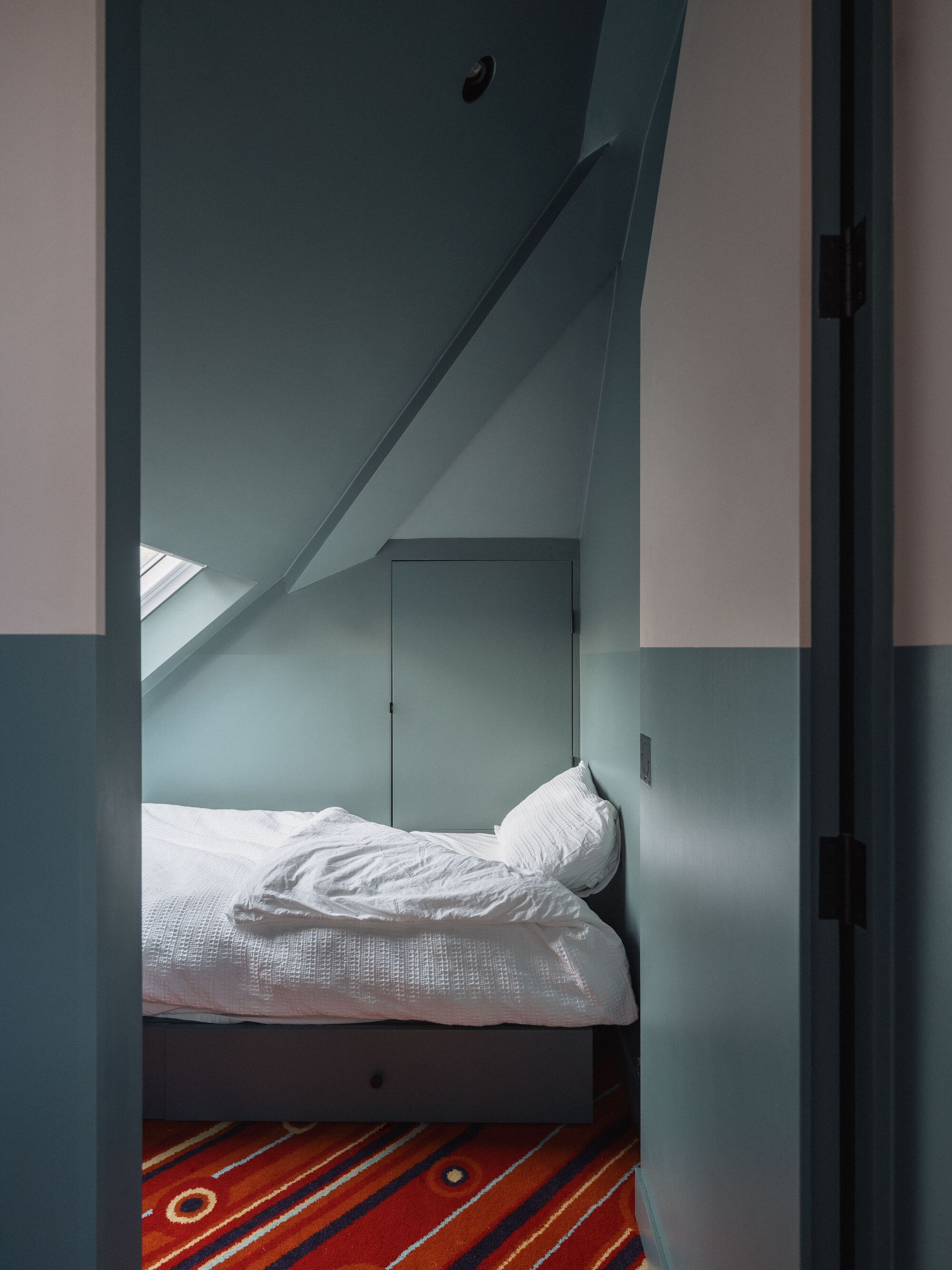 Doorway view into a small bedroom with sloped ceiling and skylight