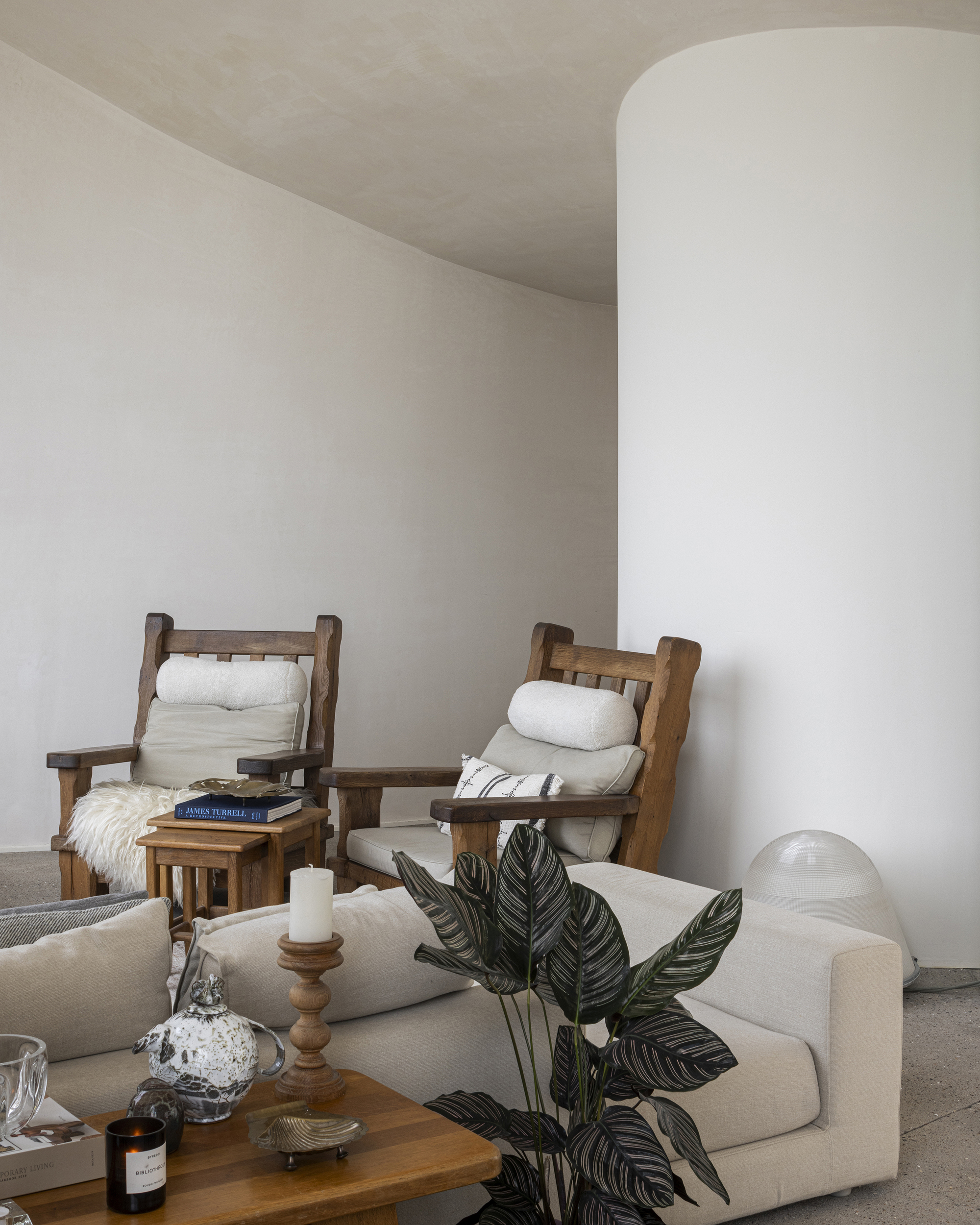 White cylindrical column beside seating area with indoor plant and arched ceiling above