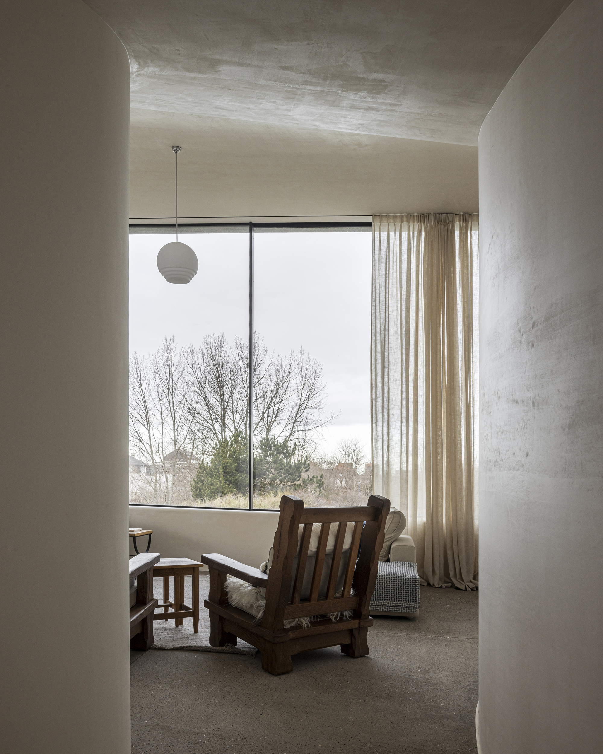 Room framed by curved plaster walls with large window overlooking bare winter trees