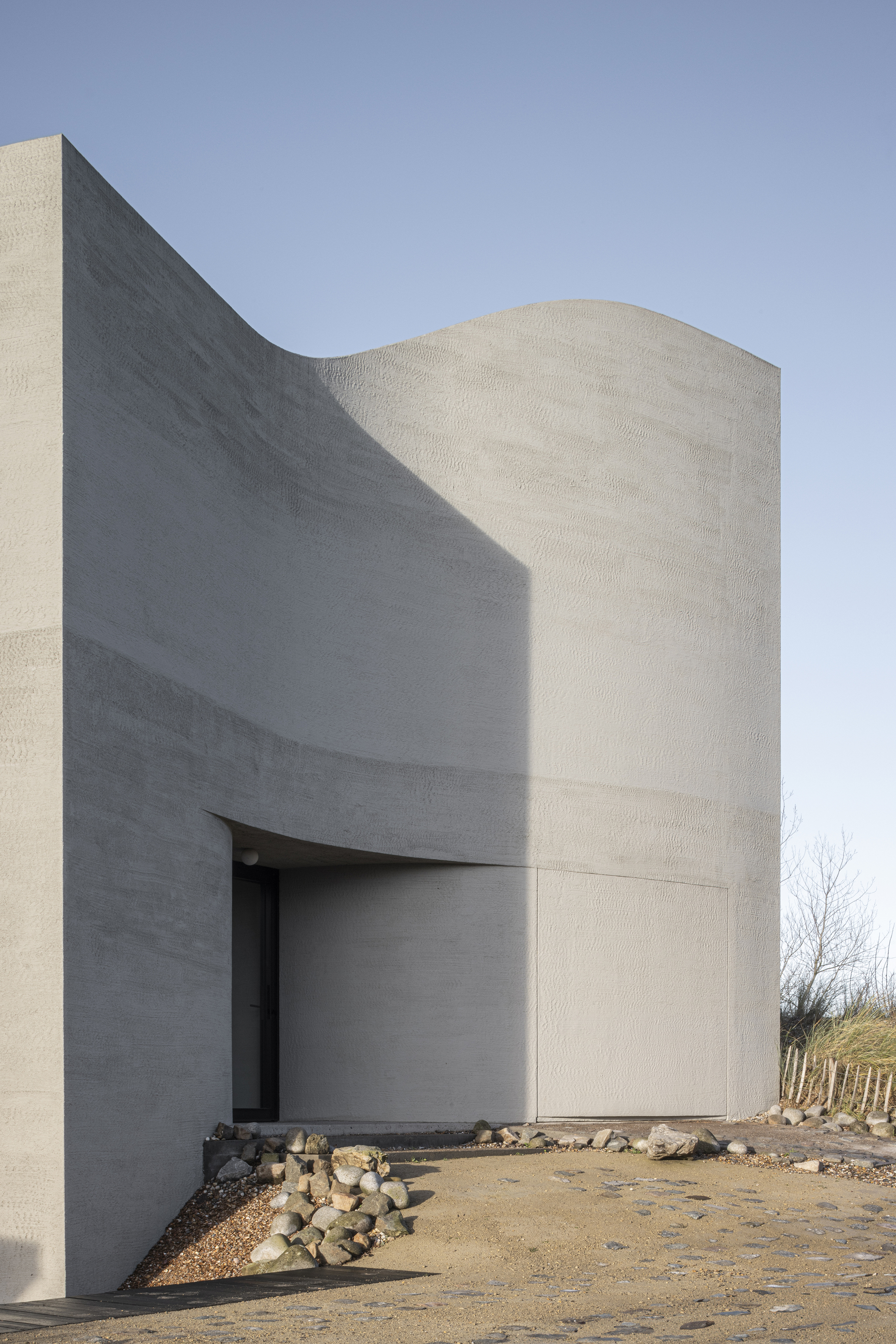 Exterior view of the curved concrete volumes with recessed entrance and cylindrical tower