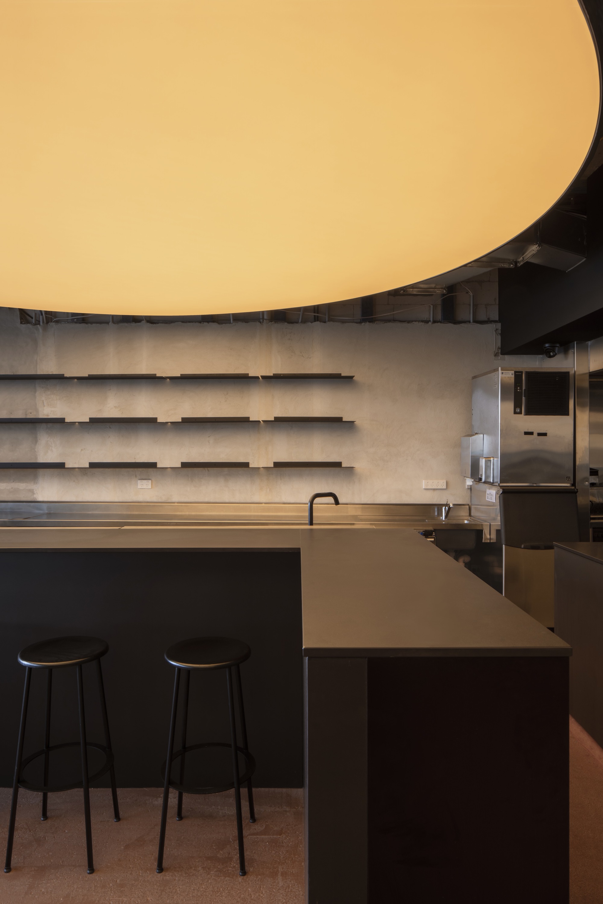 Bar counter detail showing horizontal concrete shelving and curved illuminated ceiling above