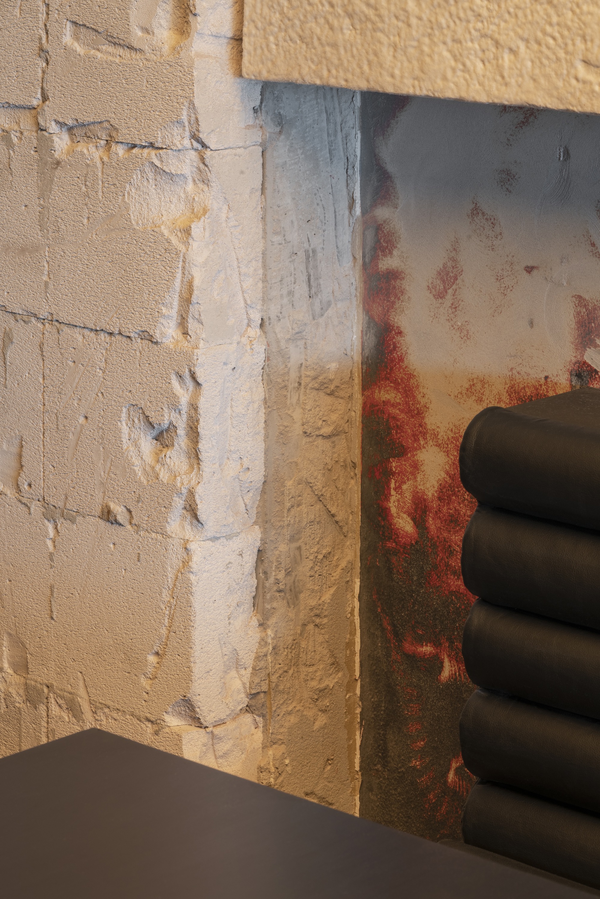 Junction of exposed brick and patinated metal panel with black pipes in afternoon light