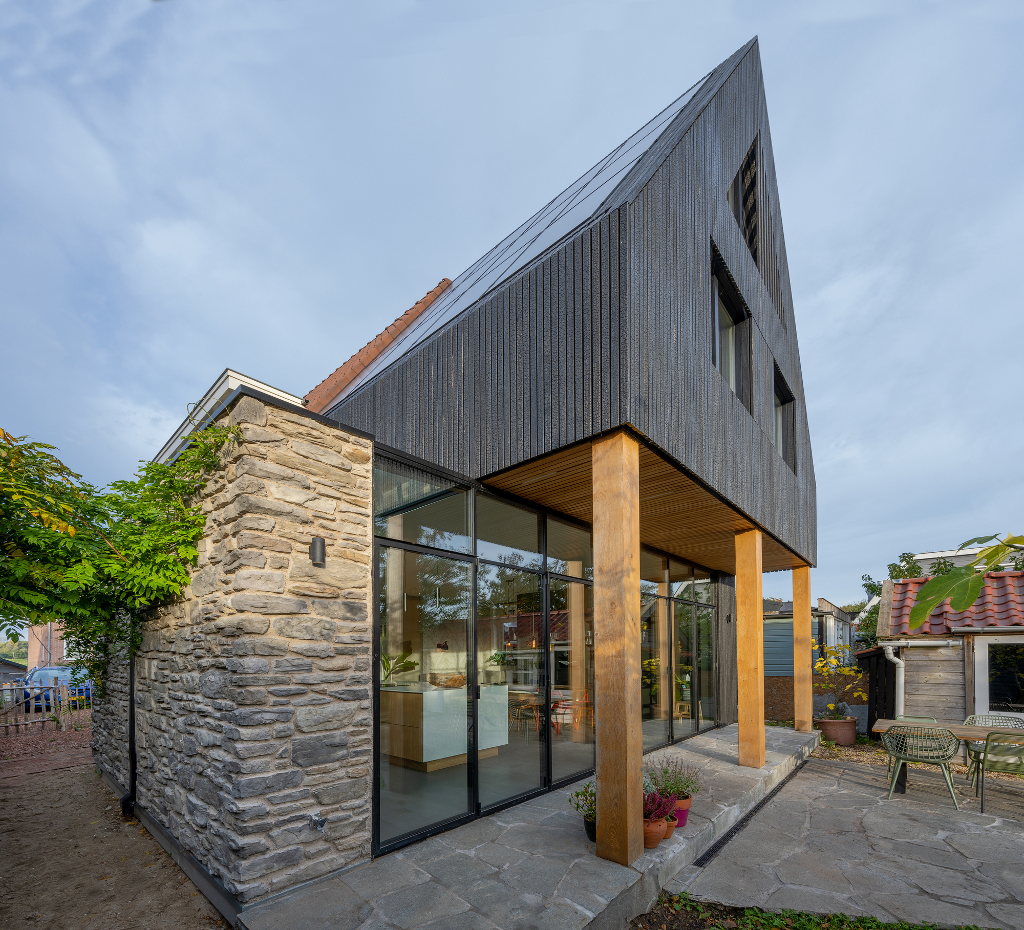 Cantilevered timber soffit over the glazed ground floor next to the existing stone wall