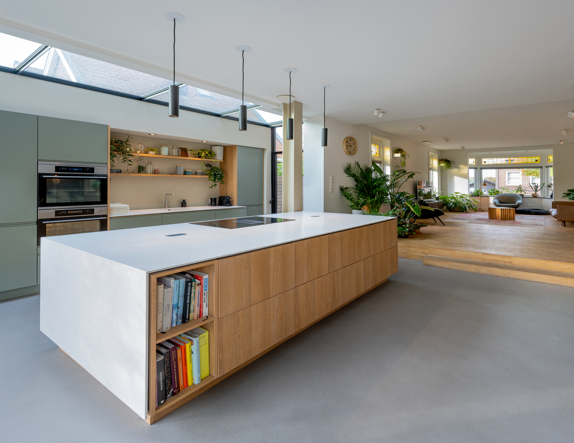 Open kitchen and living area with central island in light timber and white stone under a skylight