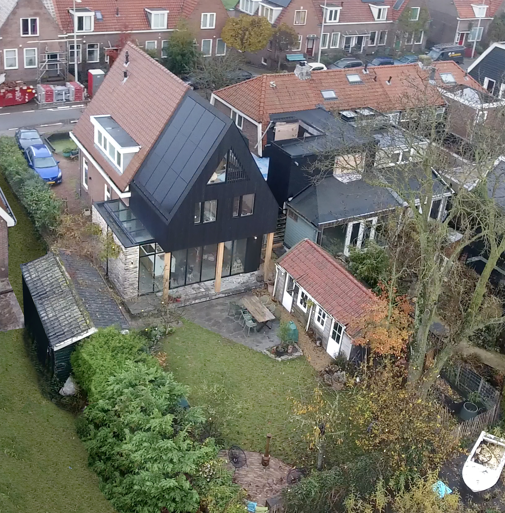 Aerial view of the dark-clad pitched roof extension among surrounding red-tiled rooftops in autumn