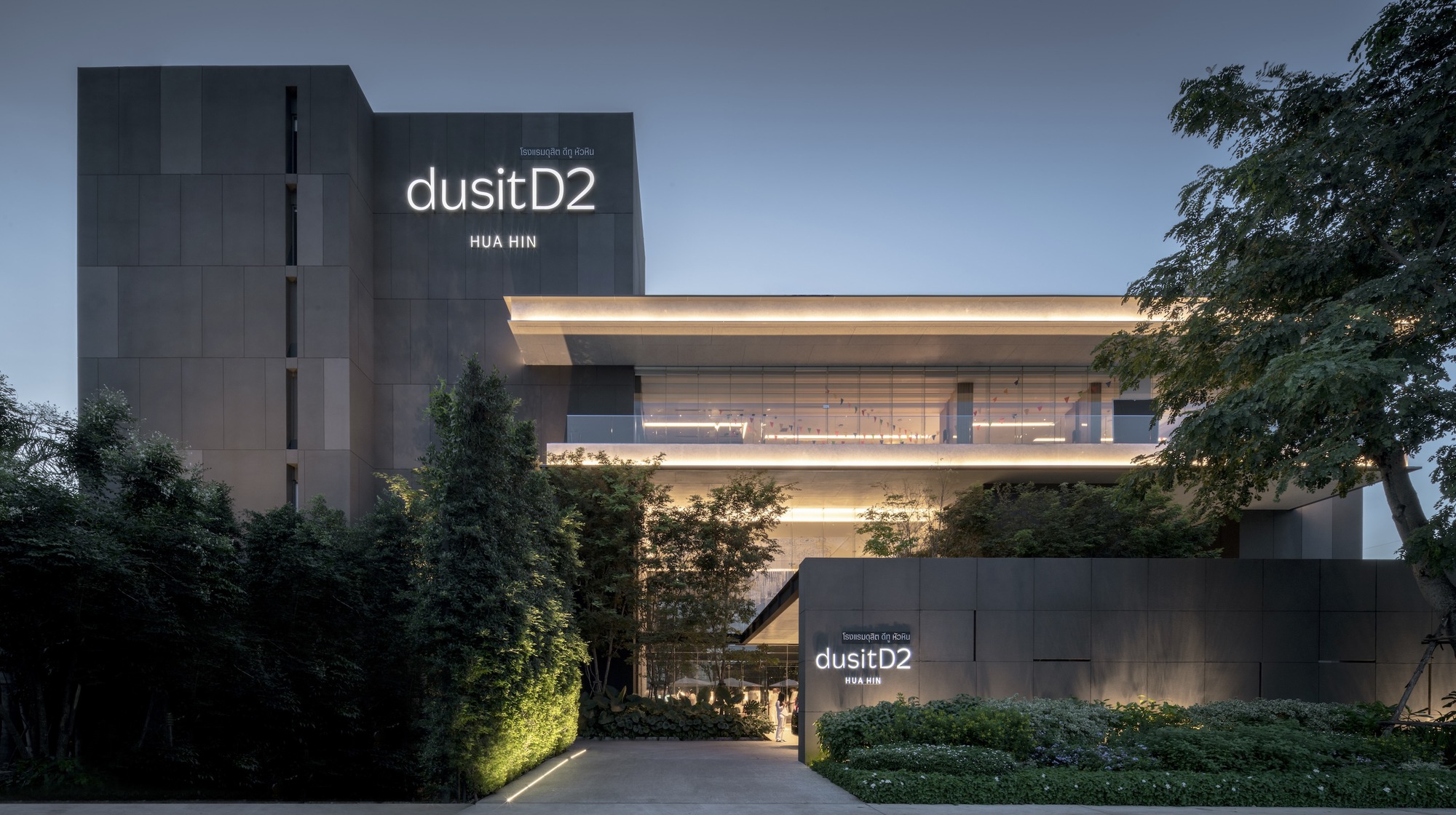 Entry drive approaching the cantilevered horizontal volume with dark vertical tower behind