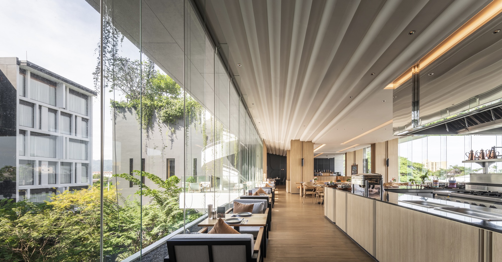 Glazed dining hall with radial ceiling fins overlooking landscaped courtyard beyond