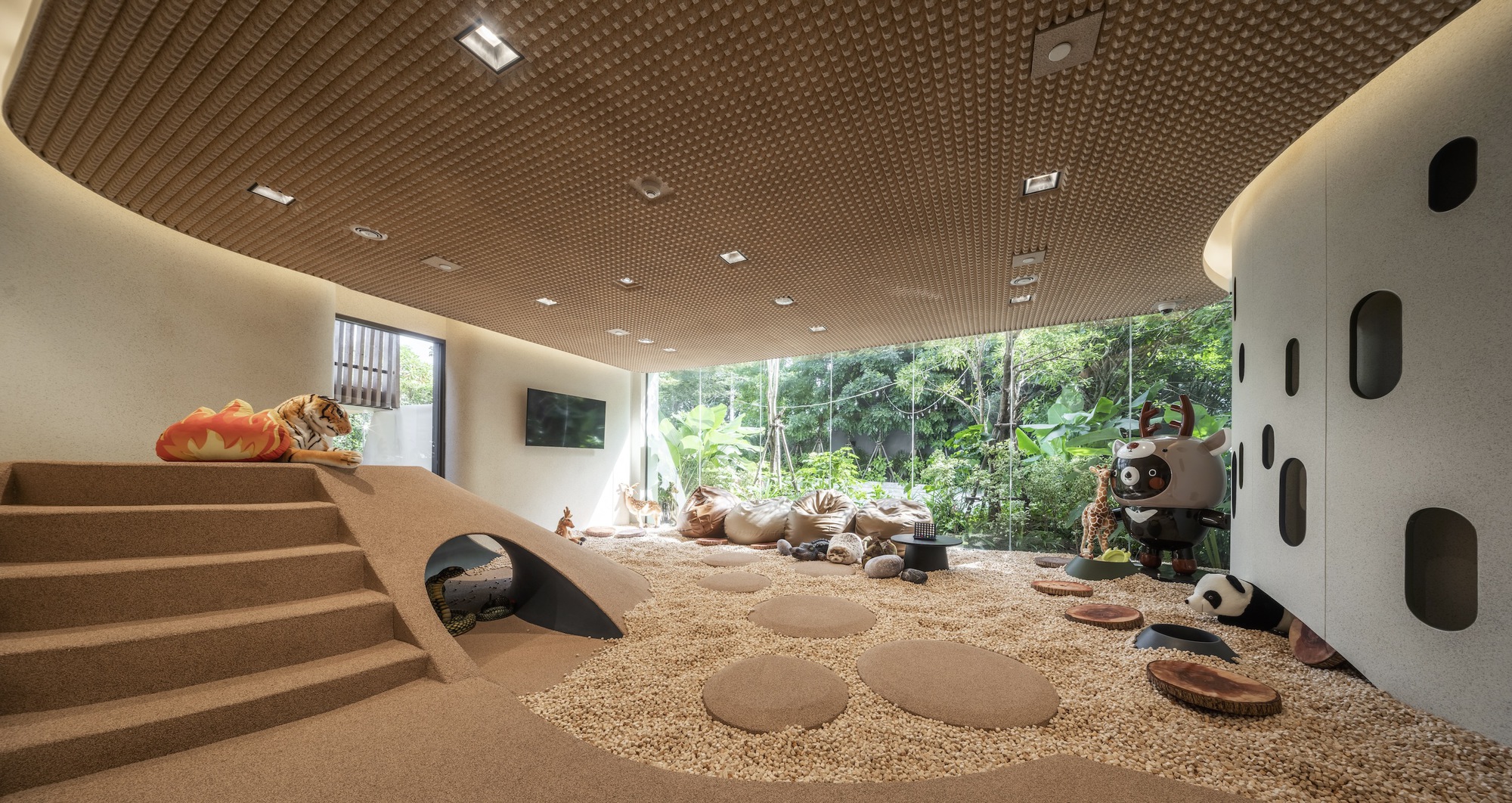 Play area with textured cork ceiling and gravel floor looking out to garden