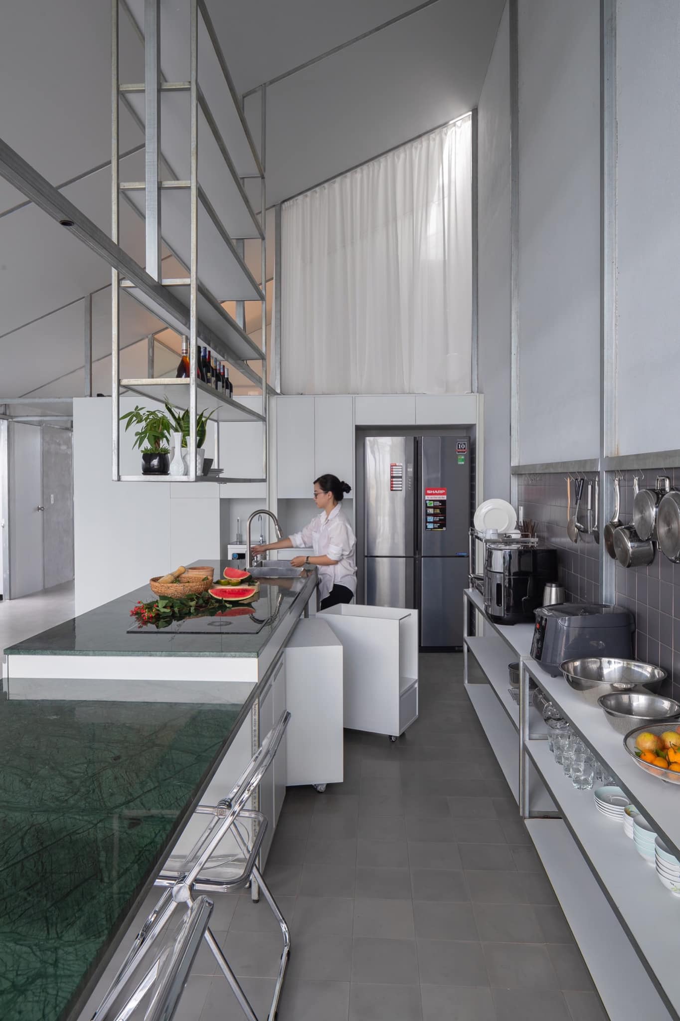 Galley kitchen with open steel shelving and double-height volume visible above white cabinetry
