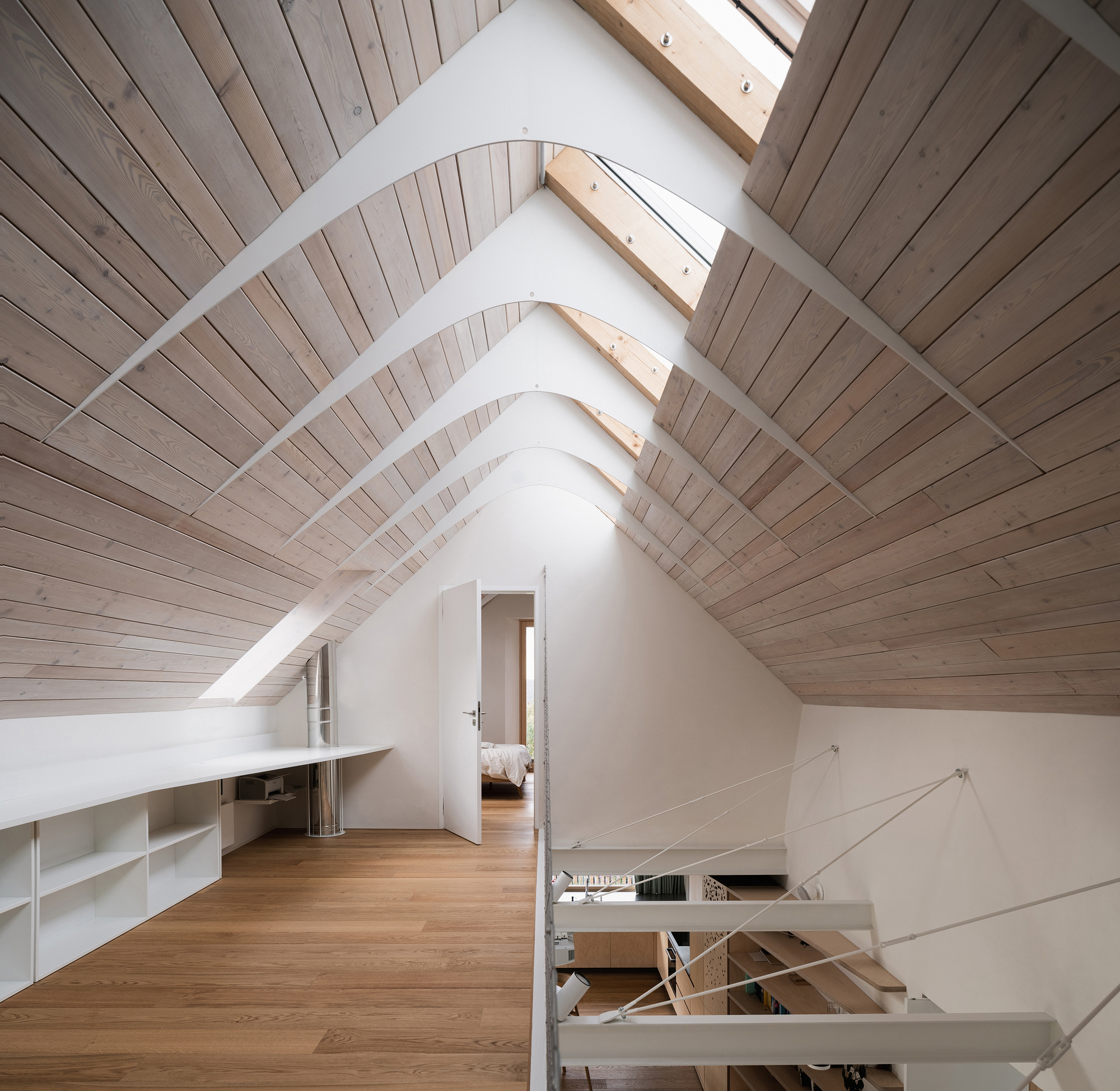 Attic space with timber-lined pitched ceiling, skylights and view through to bedroom