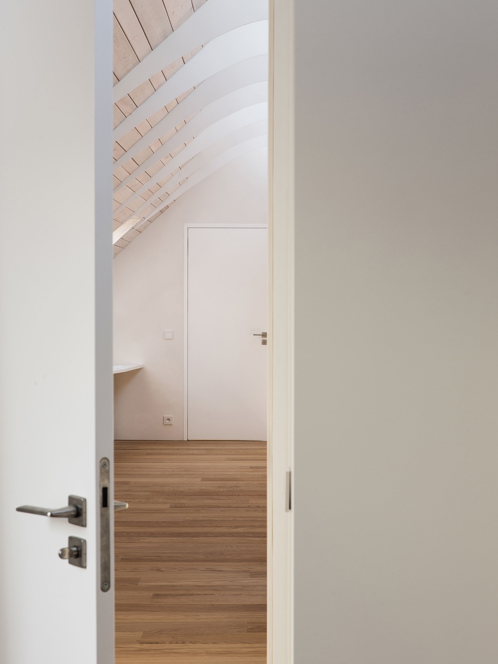 View through open doorways showing timber flooring and whitewashed timber slat ceiling under pitched roof