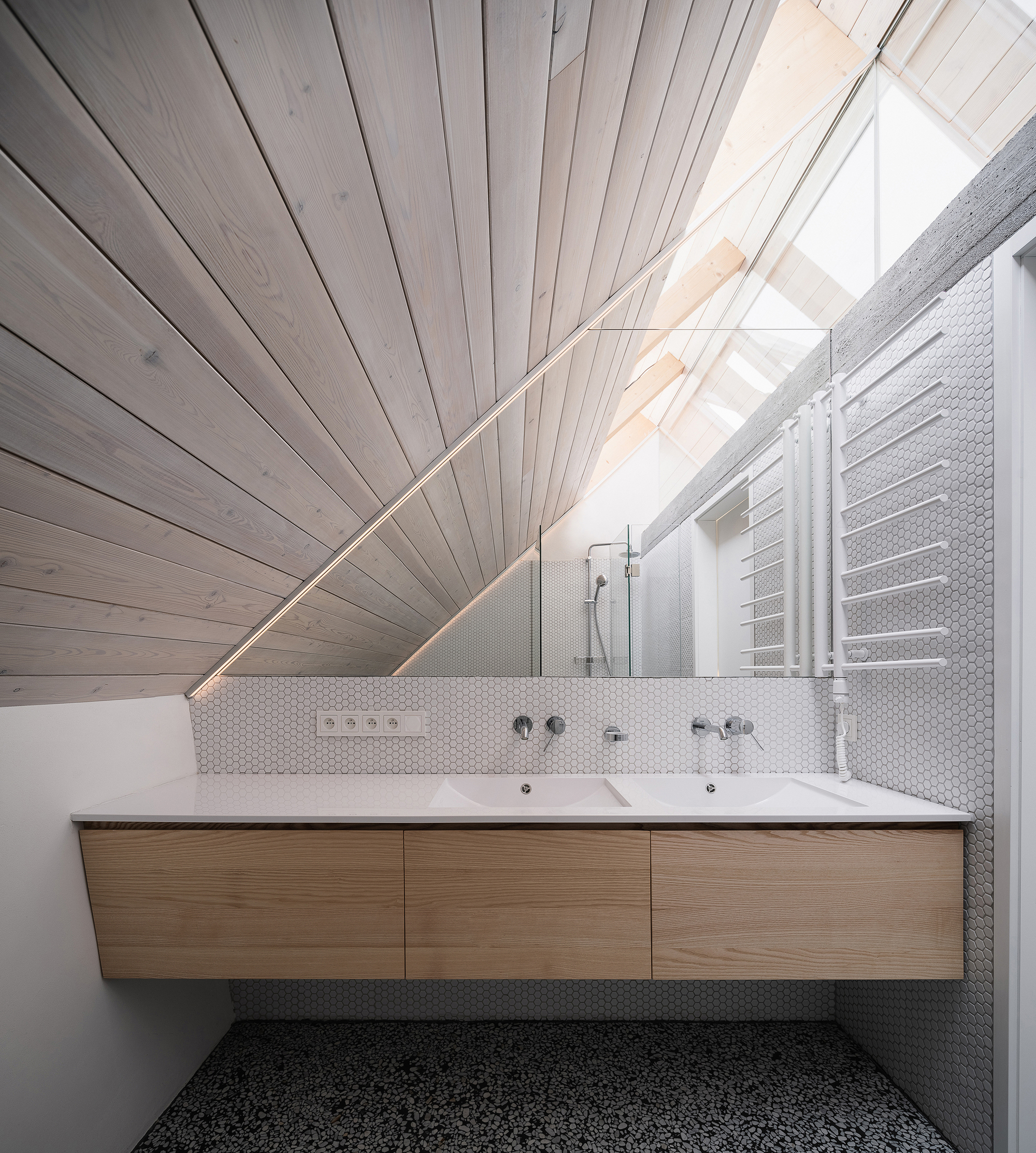 Bathroom with floating timber vanity beneath a white-painted timber ceiling sloping to a skylight