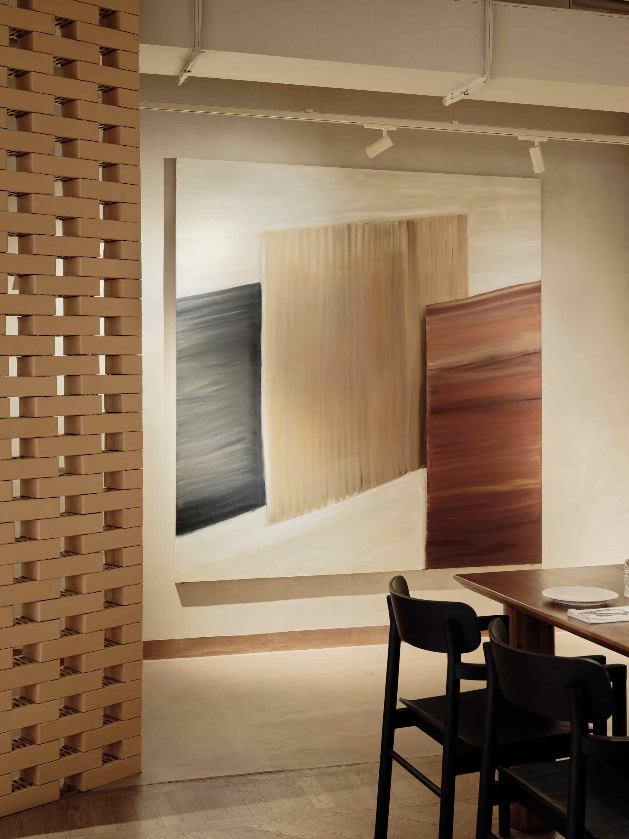 Doorway framed by a basketweave timber screen leading to a dining area with black chairs