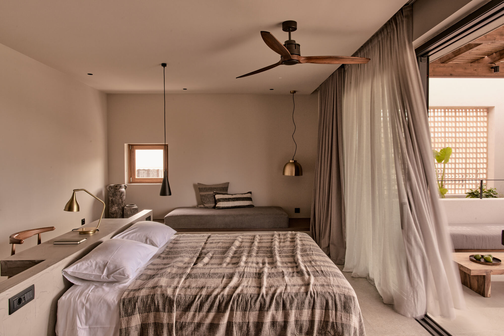Bedroom with sheer curtains dividing the sleeping area from a sitting nook with lattice screen