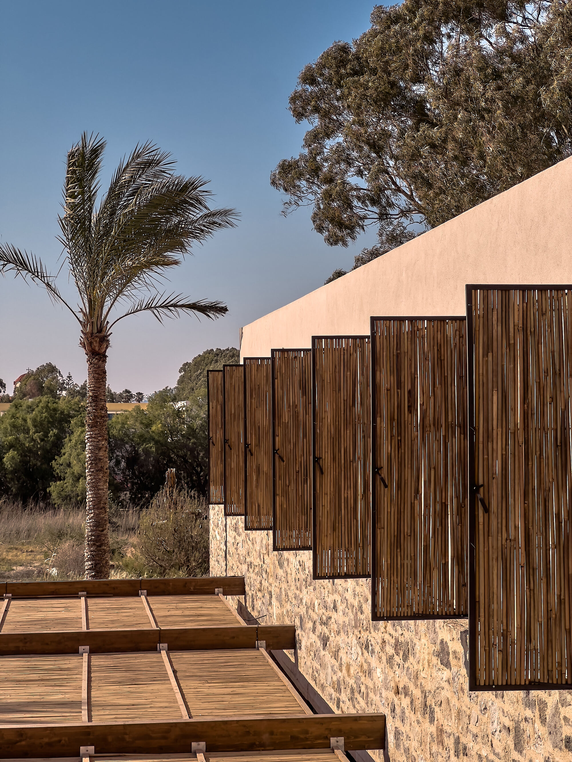 Stepped timber screens set in stone plinths ascending beside a timber deck walkway at dusk