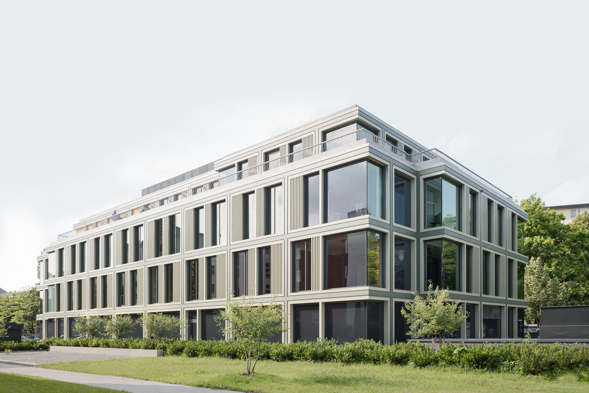 Long view of the linear facade with rhythmic window bays and planted garden in the foreground