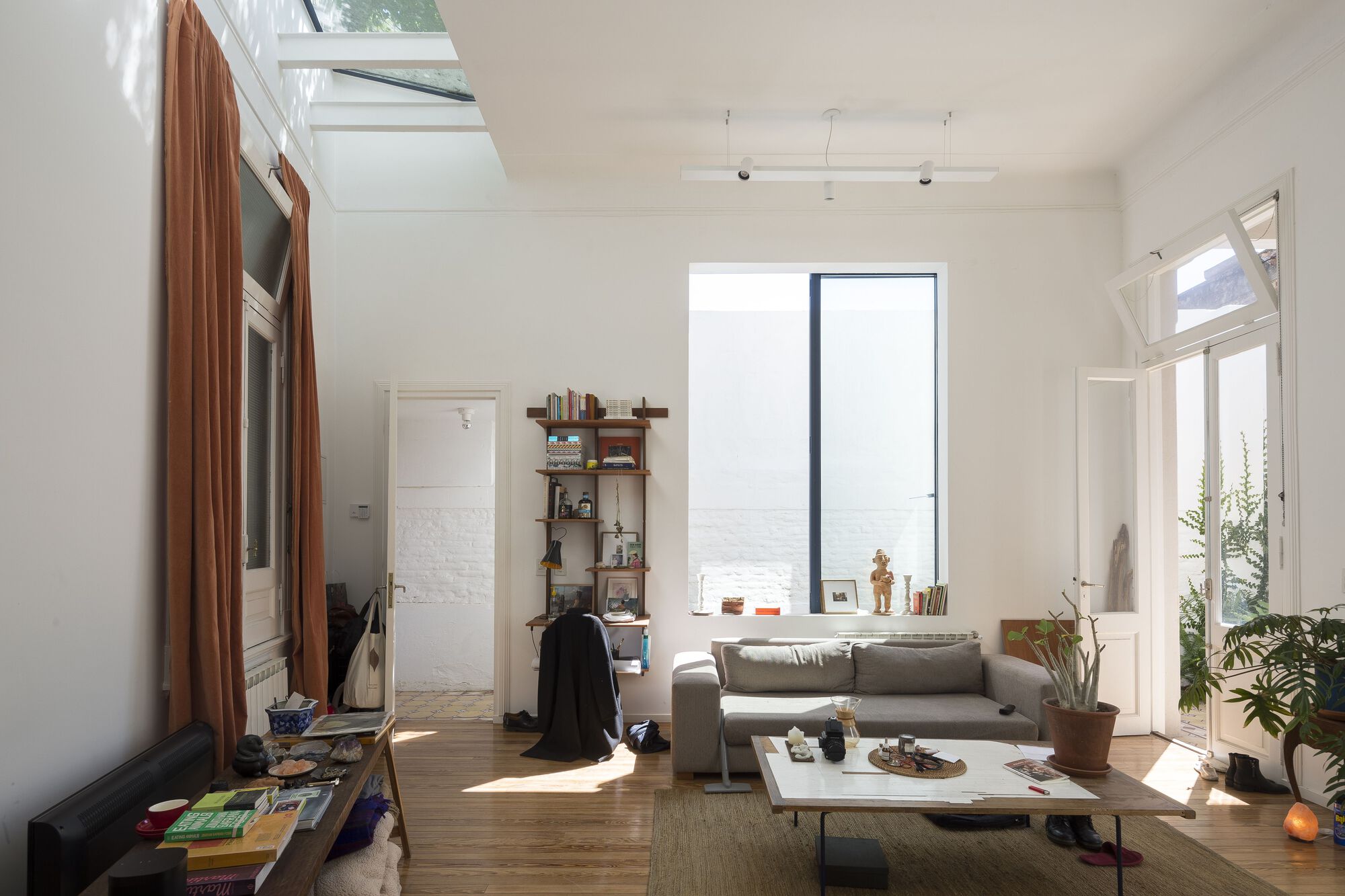 Living room with timber flooring and tall window framing a view of the sea in bright daylight