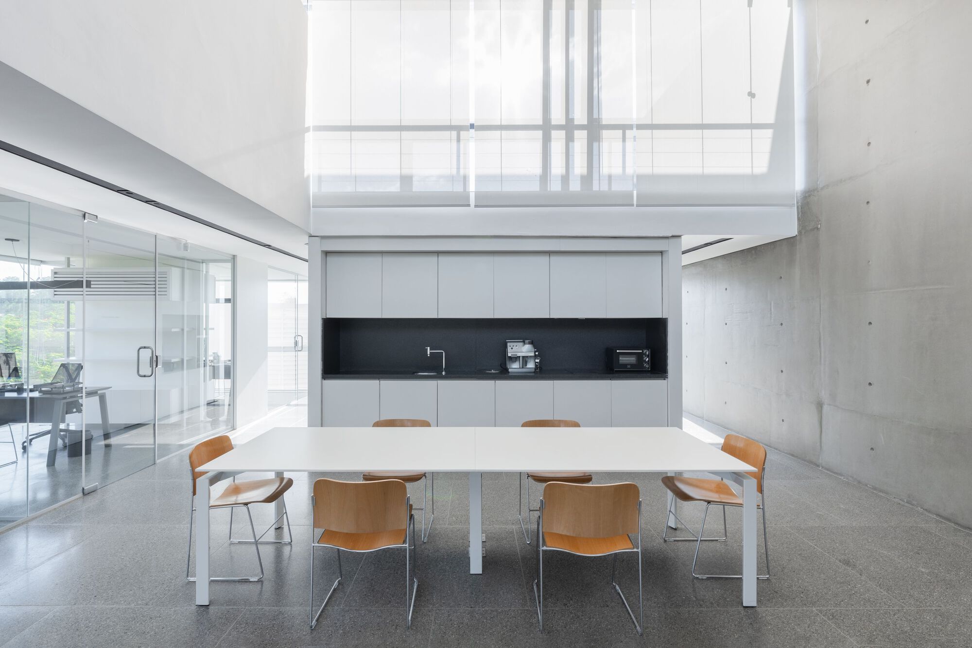 Conference area with white table and skylight above concrete walls and polished floor