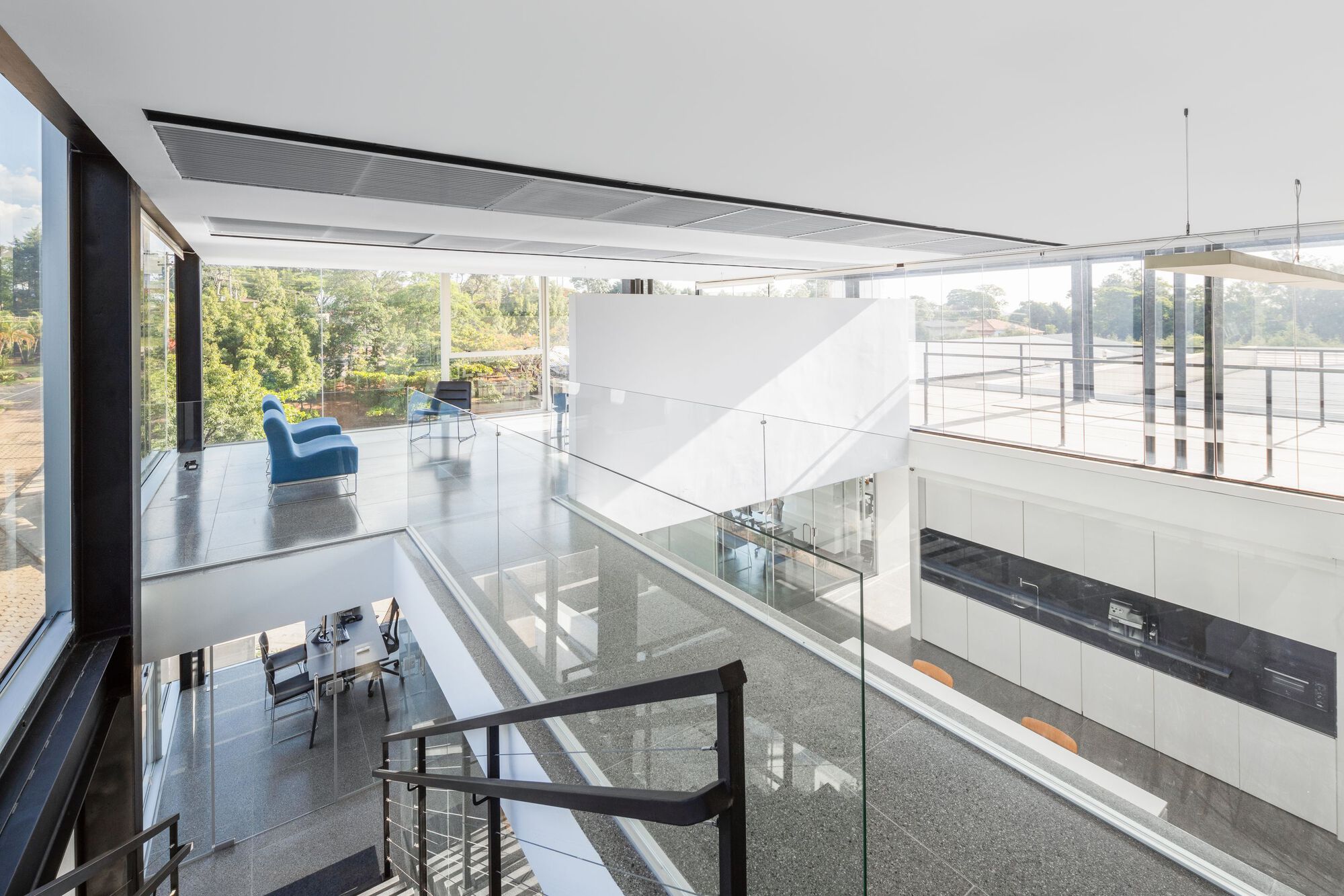 Upper level gallery with glass balustrade overlooking double-height space and exterior terrace
