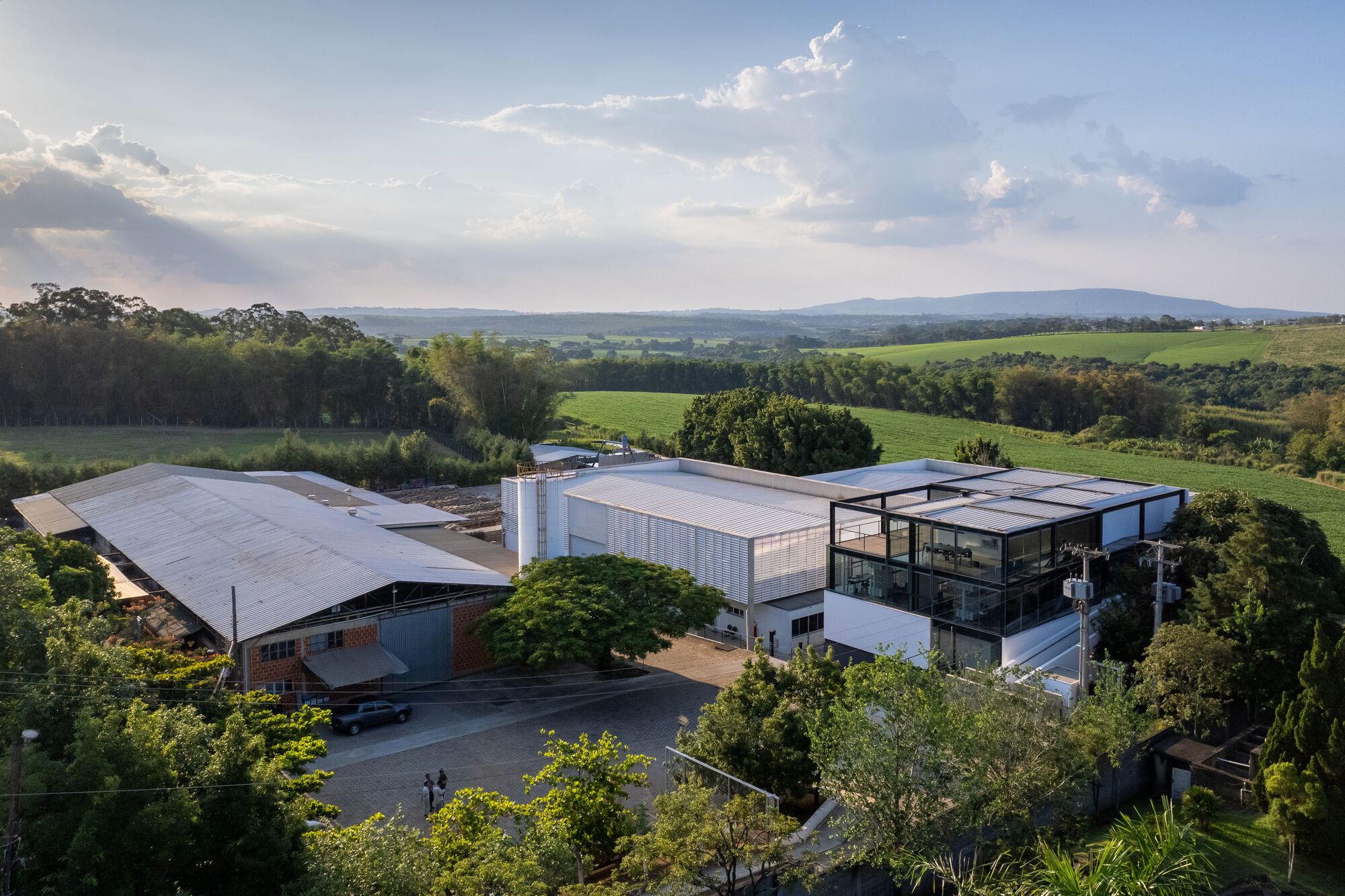 Aerial view of the industrial complex with metal roofs surrounded by green fields and trees