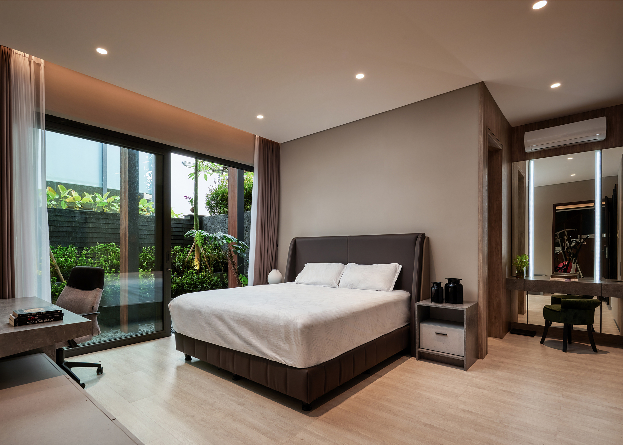Bedroom with floor-to-ceiling glazing opening to a garden courtyard with tropical plantings