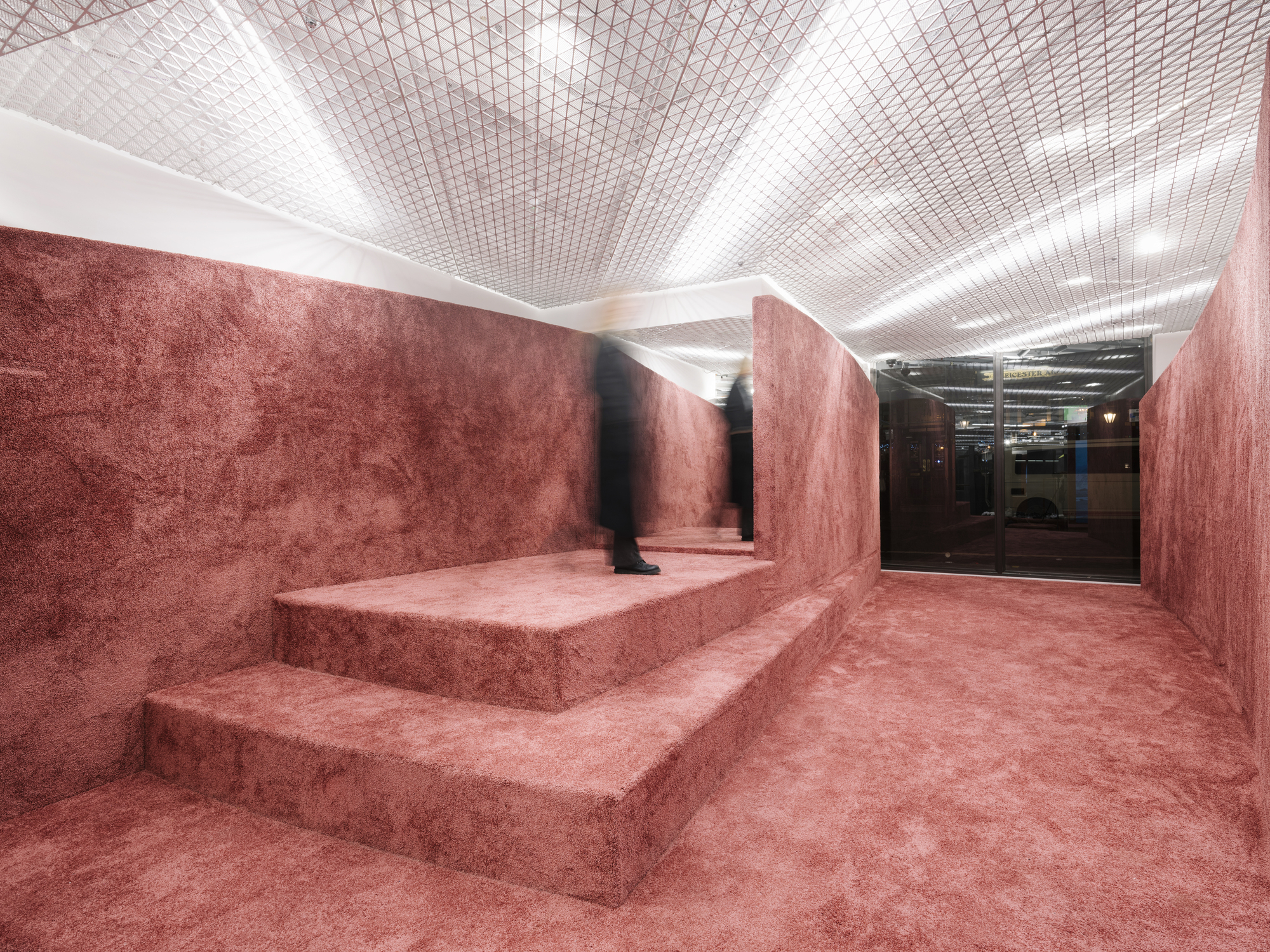 Stepped platform clad entirely in red textured material with a figure standing near the uppermost level