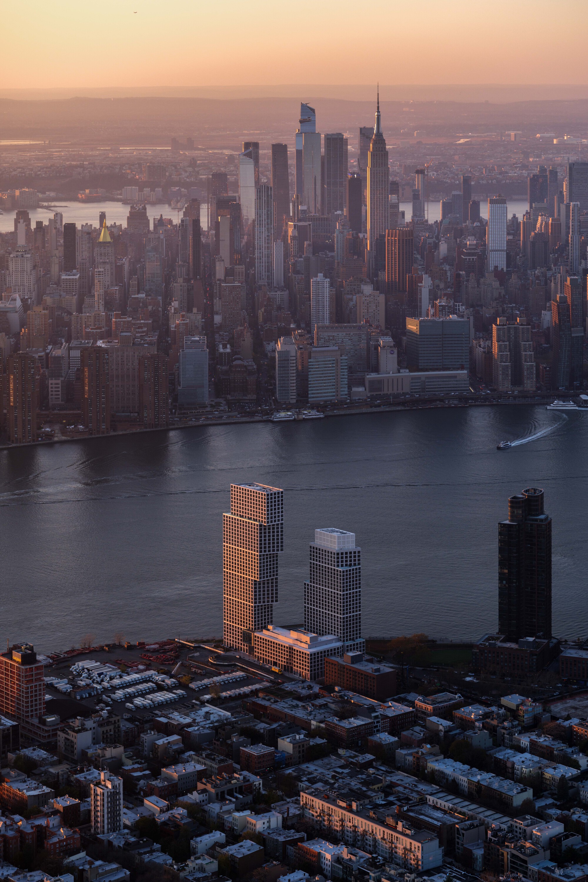 Aerial view of twin residential towers catching golden hour light above the waterfront skyline