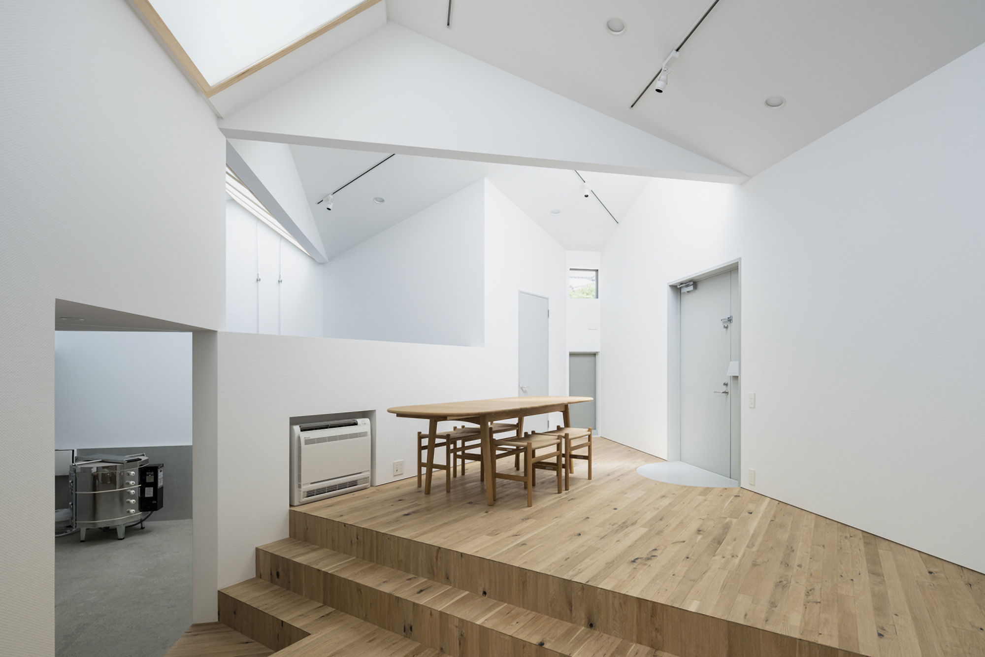 Raised timber platform with dining table and chairs beneath a vaulted ceiling with skylights