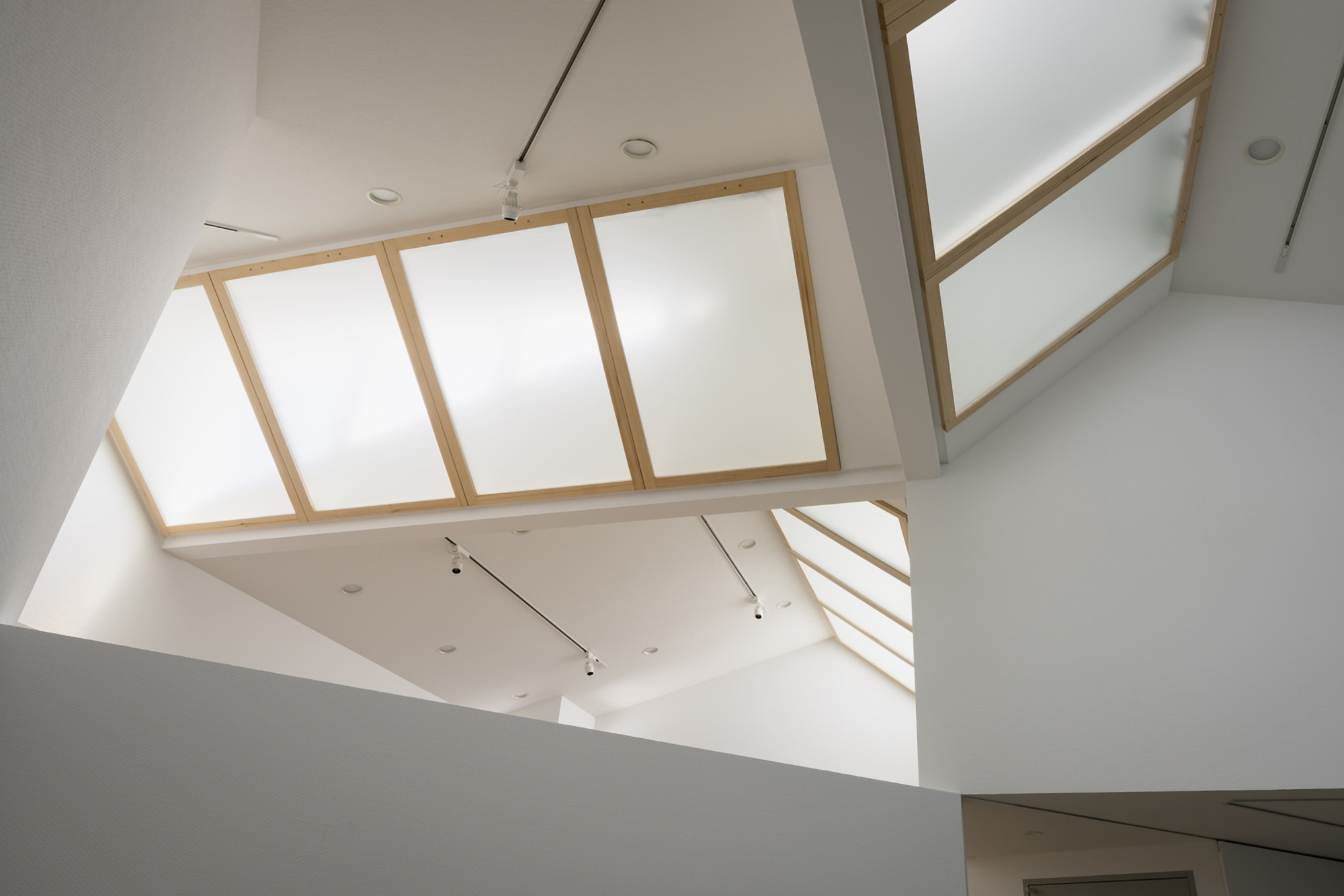 Upward view of timber-framed skylights and white walls in a multi-level interior volume