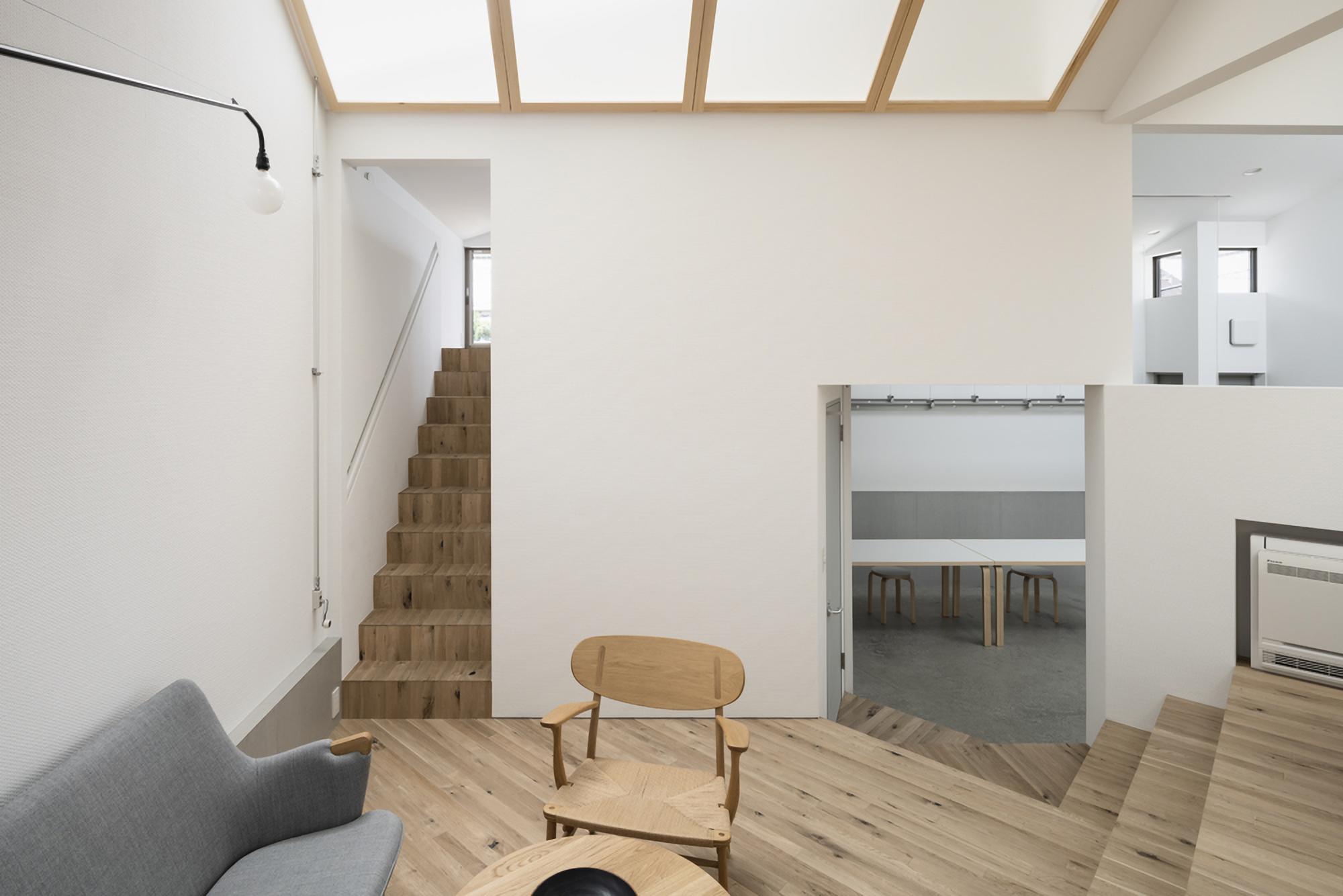Living area with timber staircase and sliding door opening to a dining space below skylights
