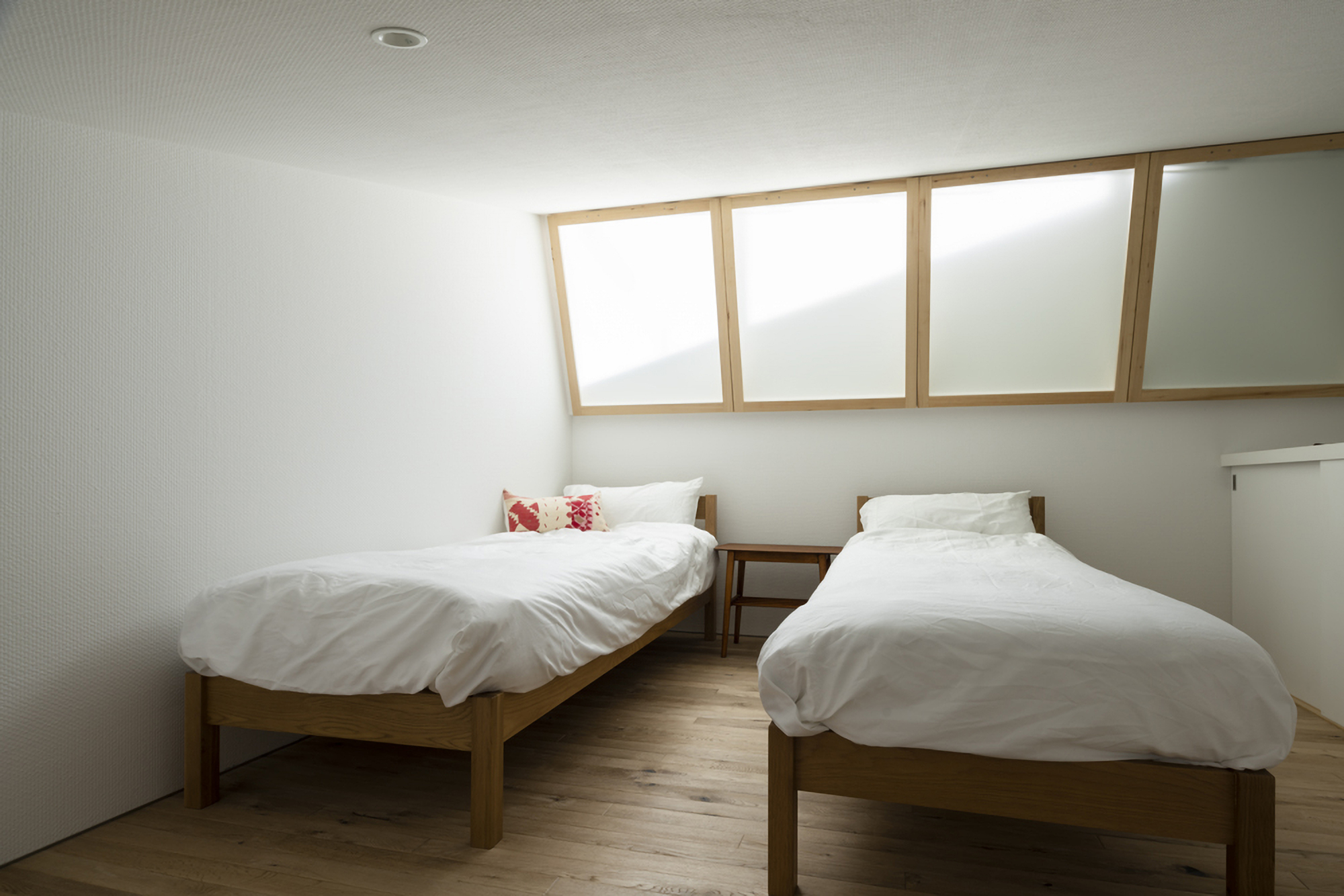 Bedroom with two timber beds beneath a ribbon of timber-framed clerestory windows